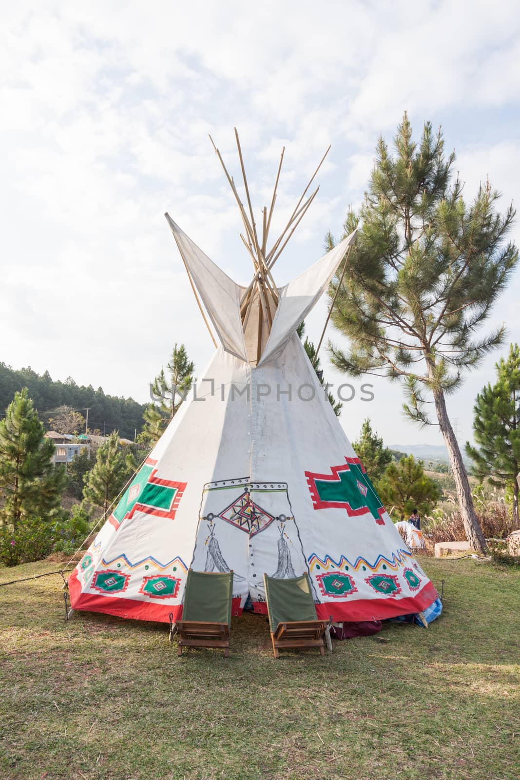 An indian teepee set up in a meadow among pine wood by kritsada1992