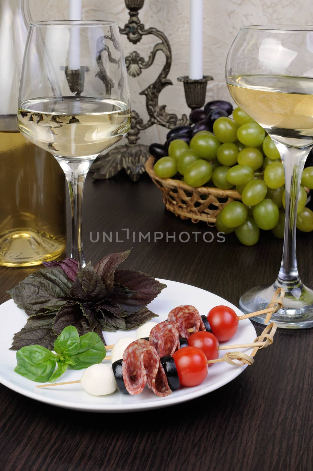 Appetizer of salami with mozzarella, olives, cherry tomatoes on skewers with basil