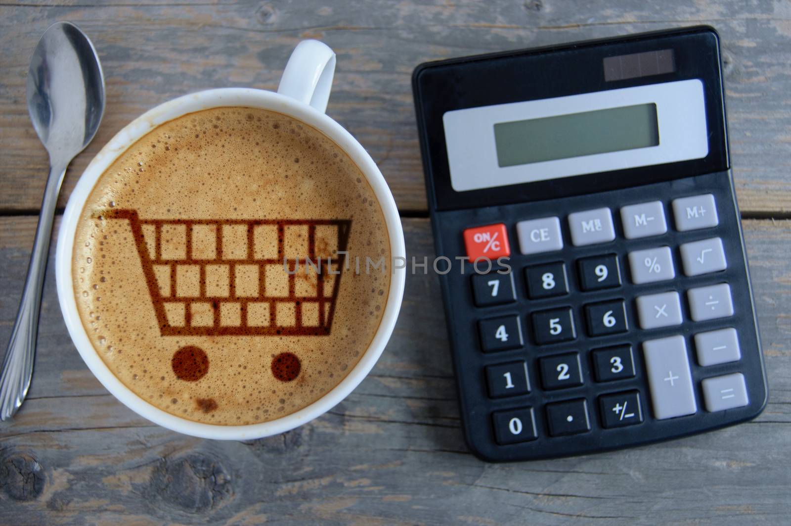 Shopping cart symbol inside a coffee cup by a calculator