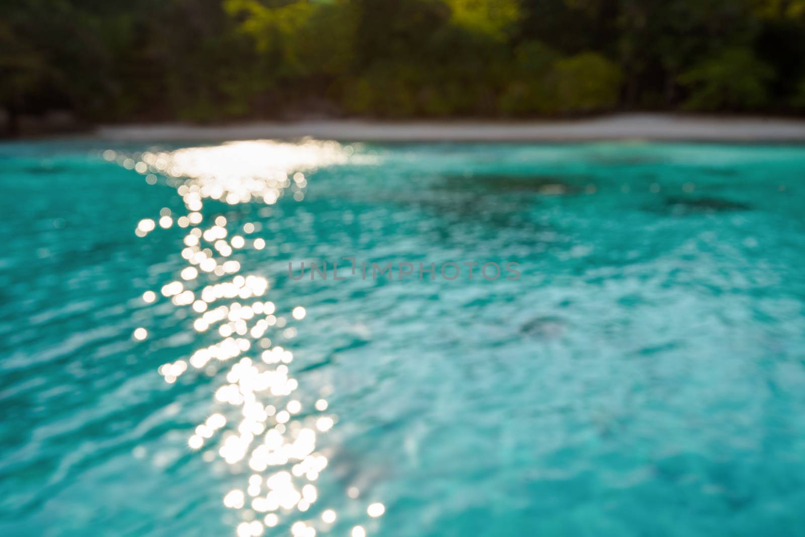 Blur beach and green blue sea surface with reflecting sunlight evening in summer for background
