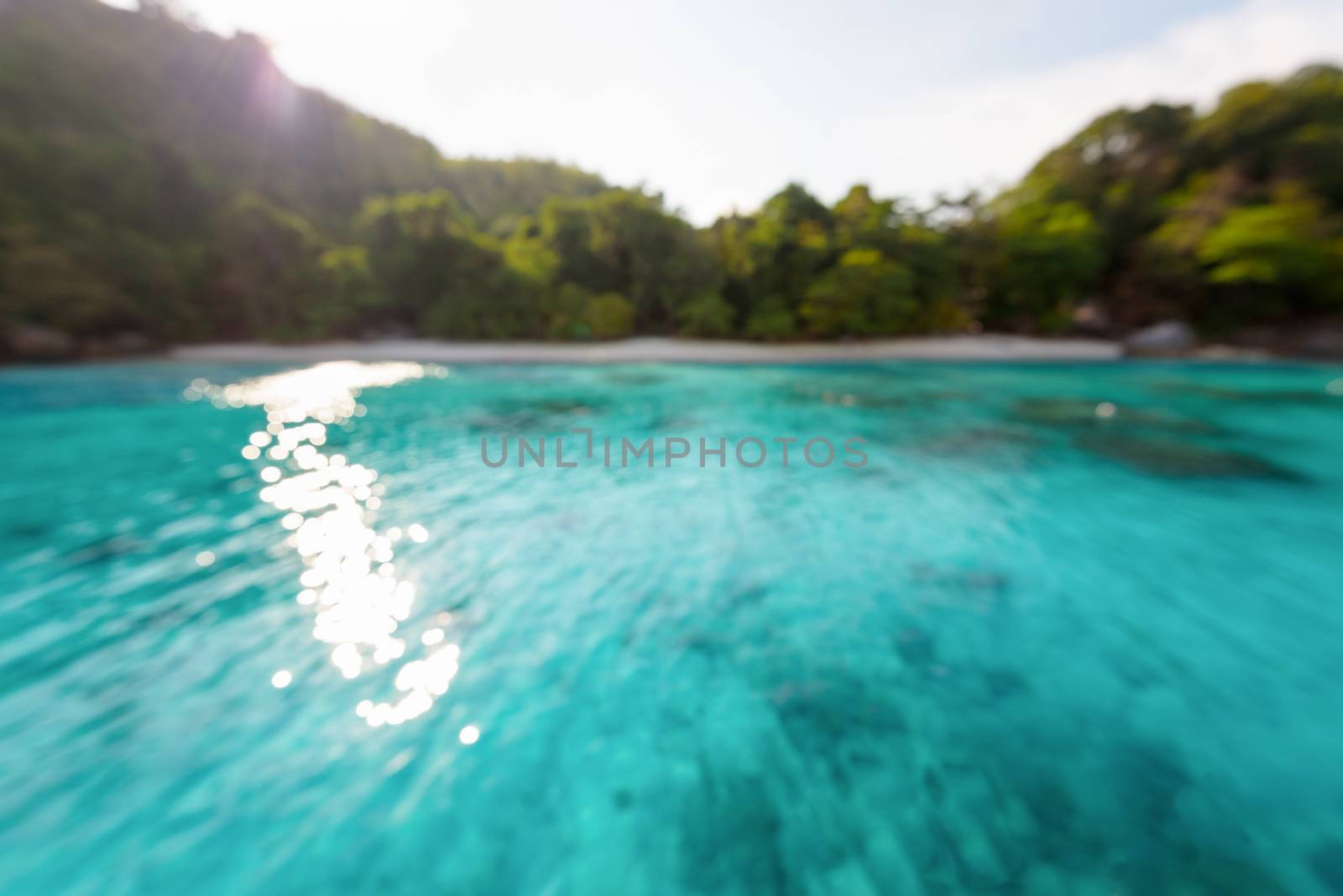 Blur beach and green blue sea surface with reflecting sunlight evening in summer for background