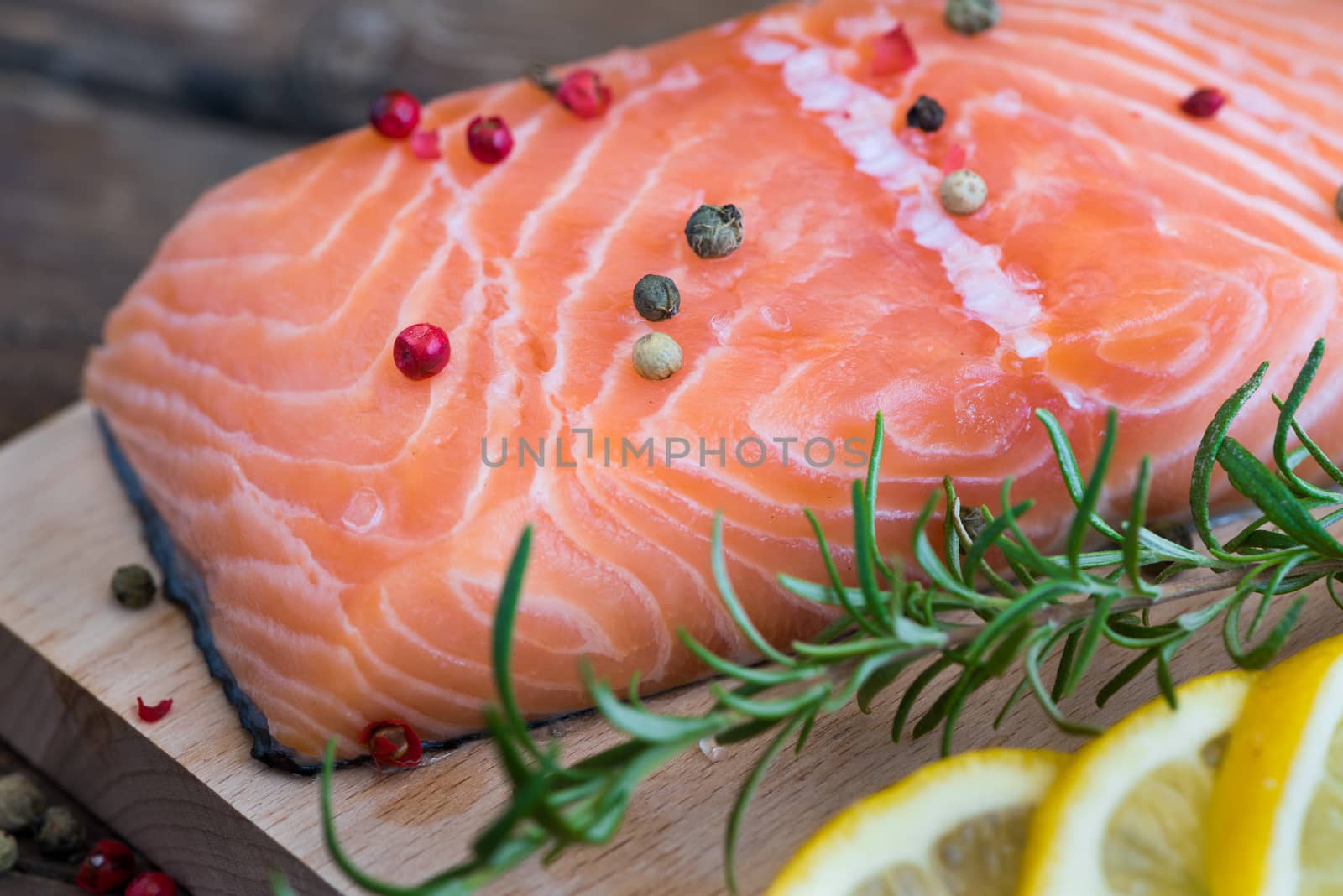 Raw Salmon Fish Fillet with Lemon, Spices and Fresh Herbs on Cutting Board
