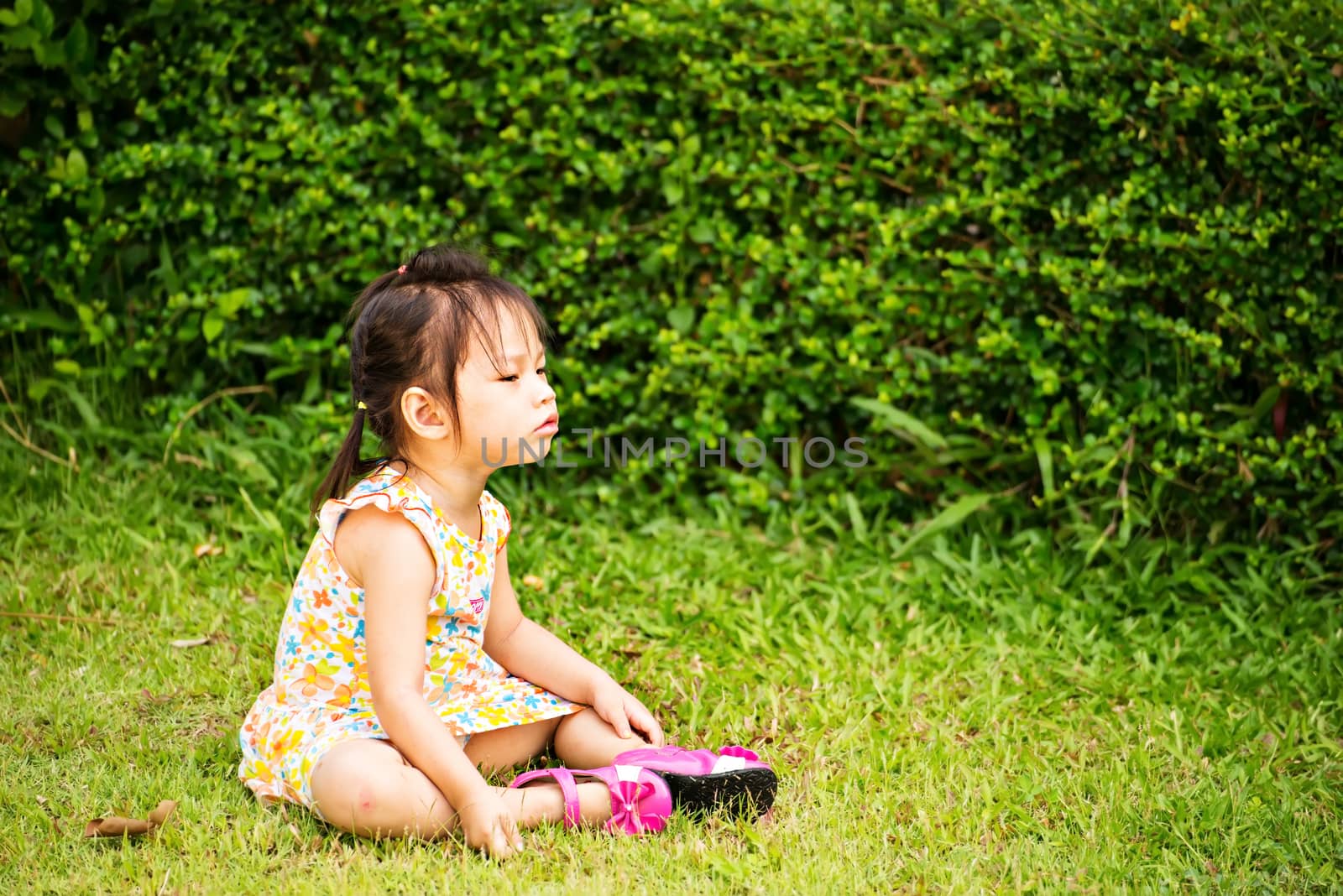 Outdoor portrait of sad little girl playing in summer park