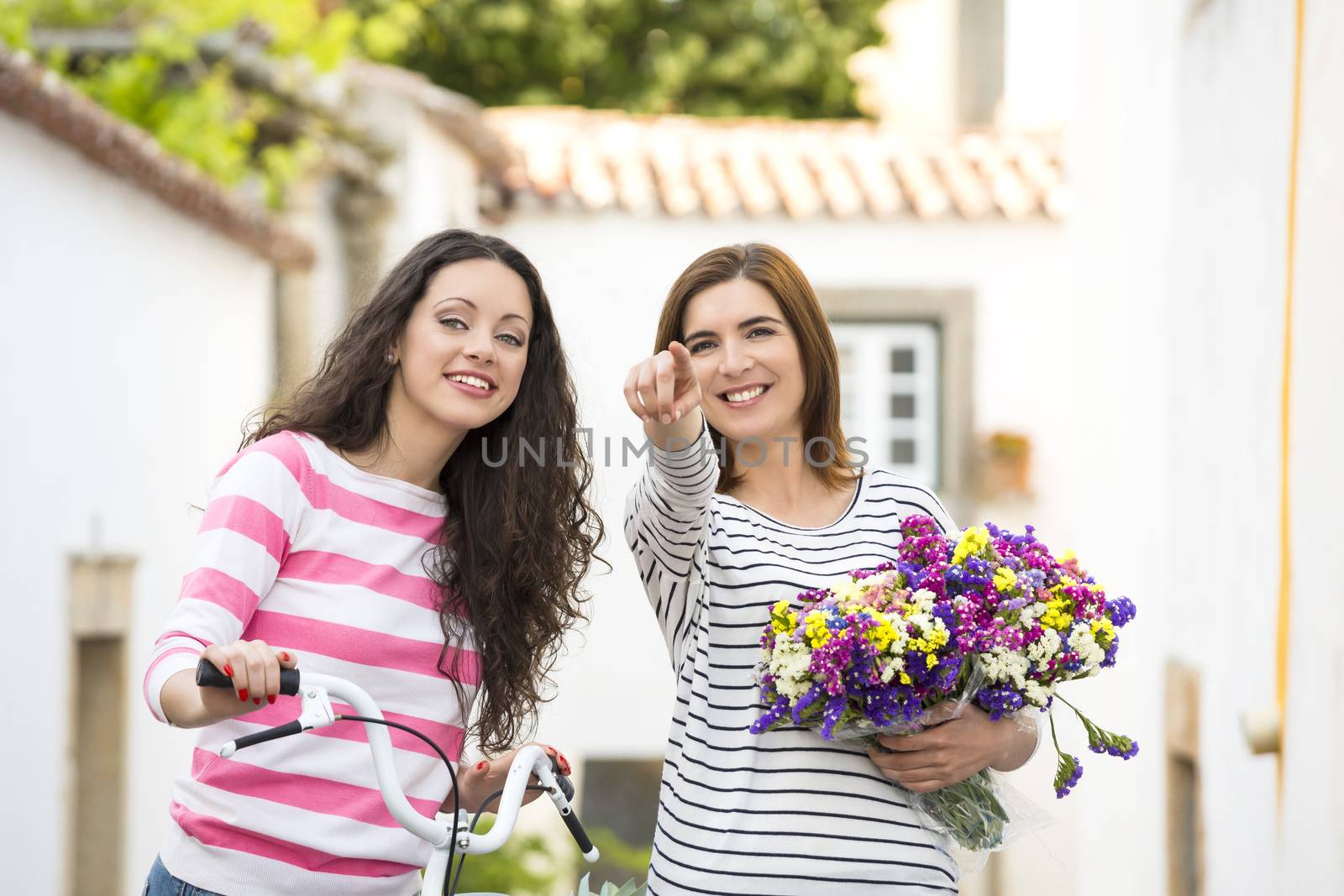 Two beautiful female friends smiling and pointing to somewhere