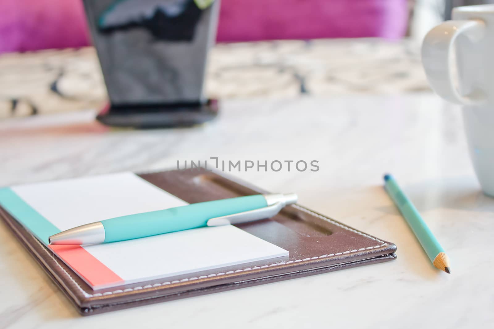 Notebook and white coffee cup on marble table