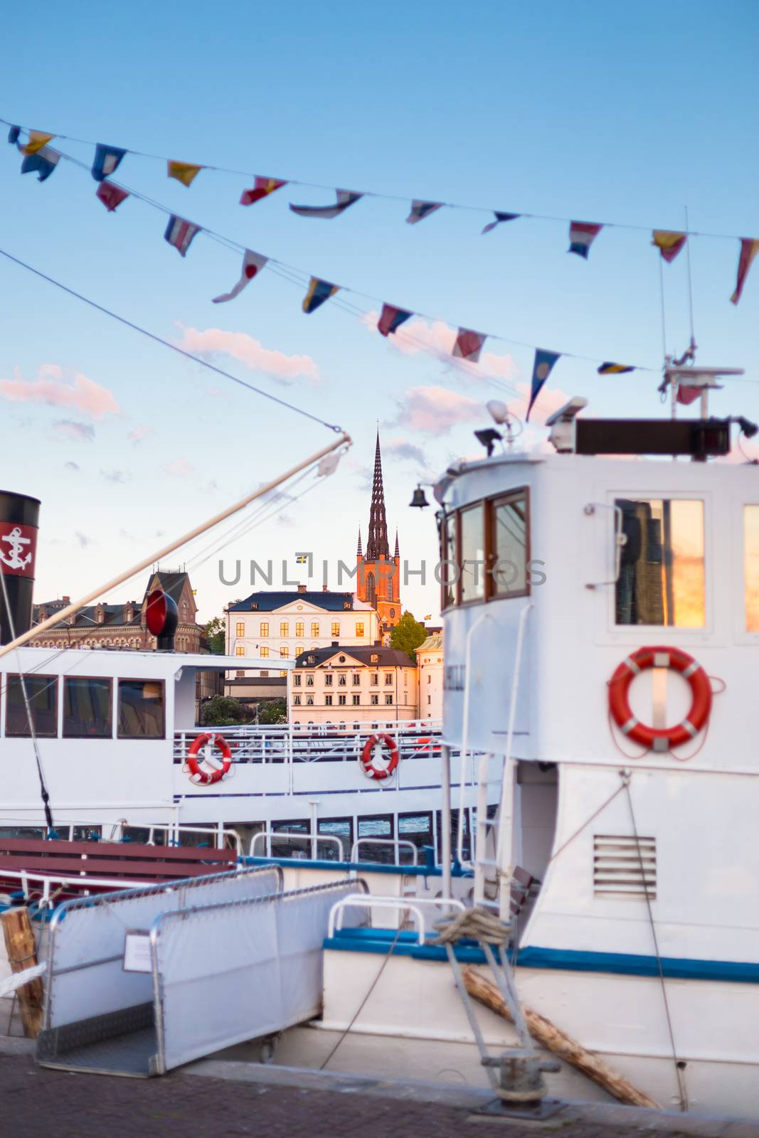 Swedish capital Stockholm in sunset. White traditional wooden  ferry steamer and old medieval downtown of Gamla stan in the background. Focus on background. Vertical composition.