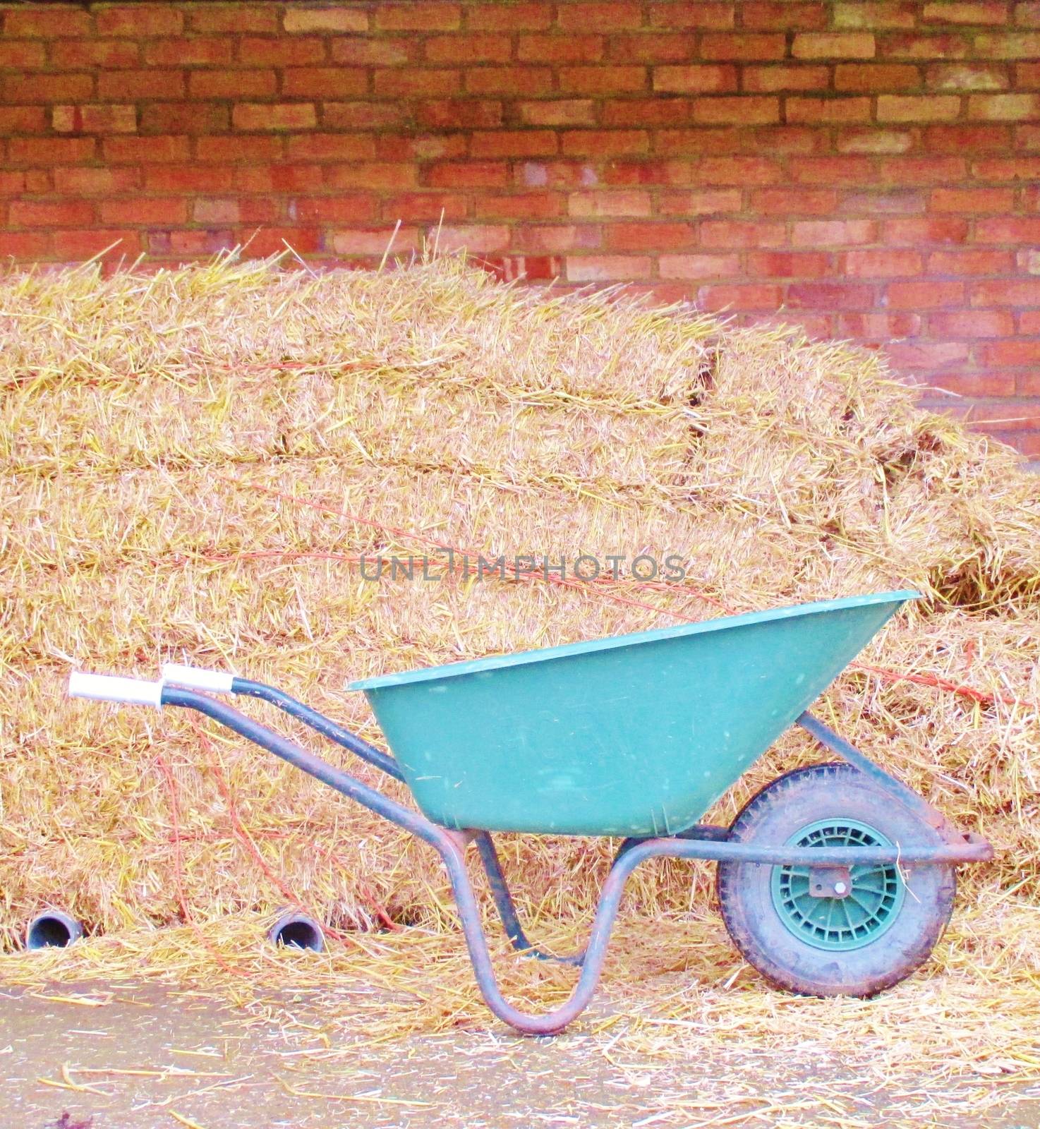 red Brick wall with hay bales and wheel barrow