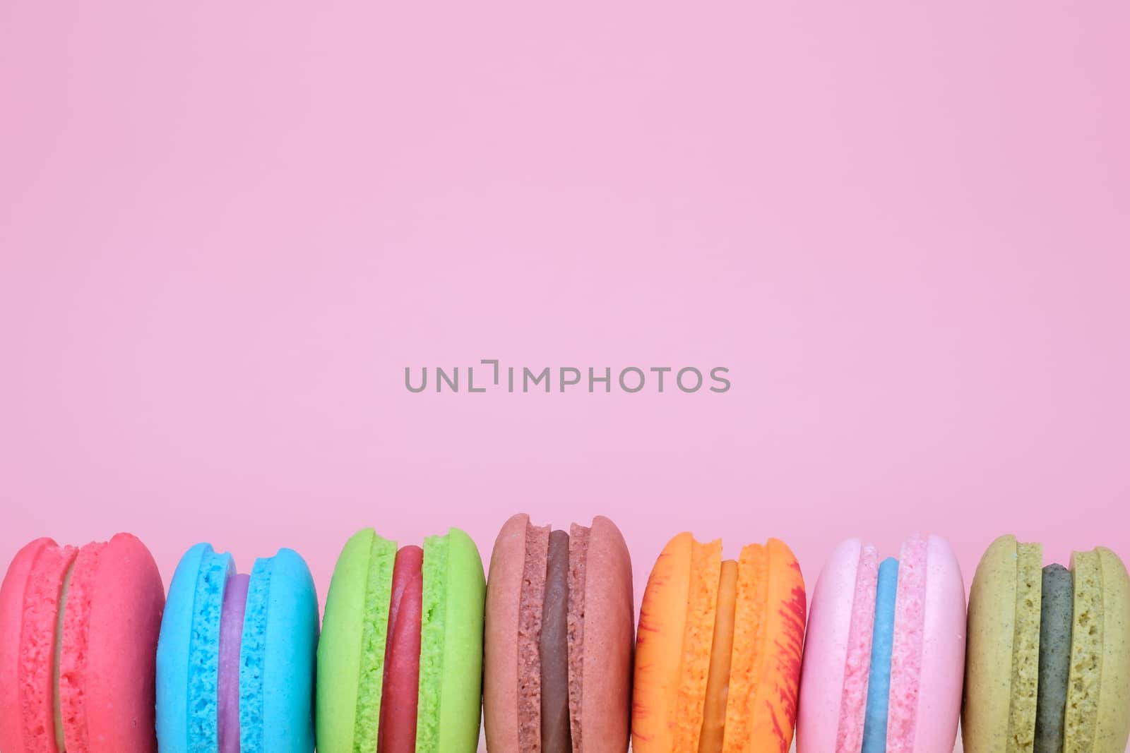 Sweet and colourful french macaroons on pastel pink background