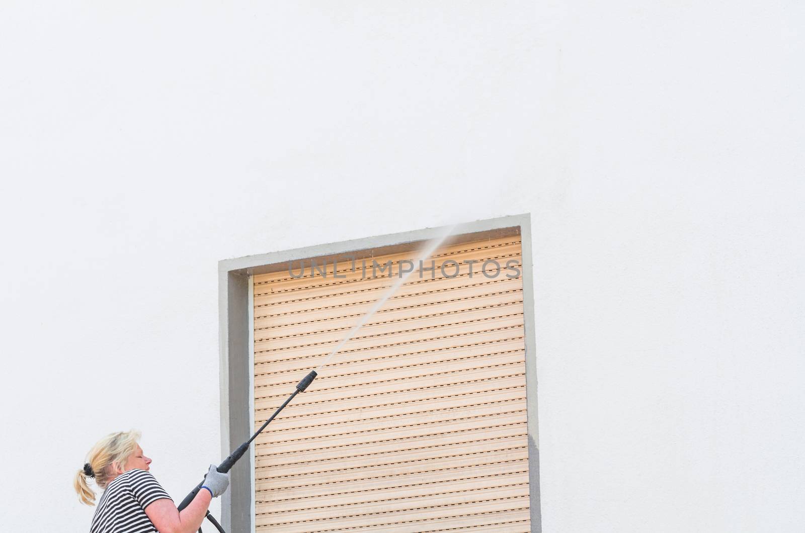 Exterior cleaning and building cleaning a gable wall with high pressure water jet.