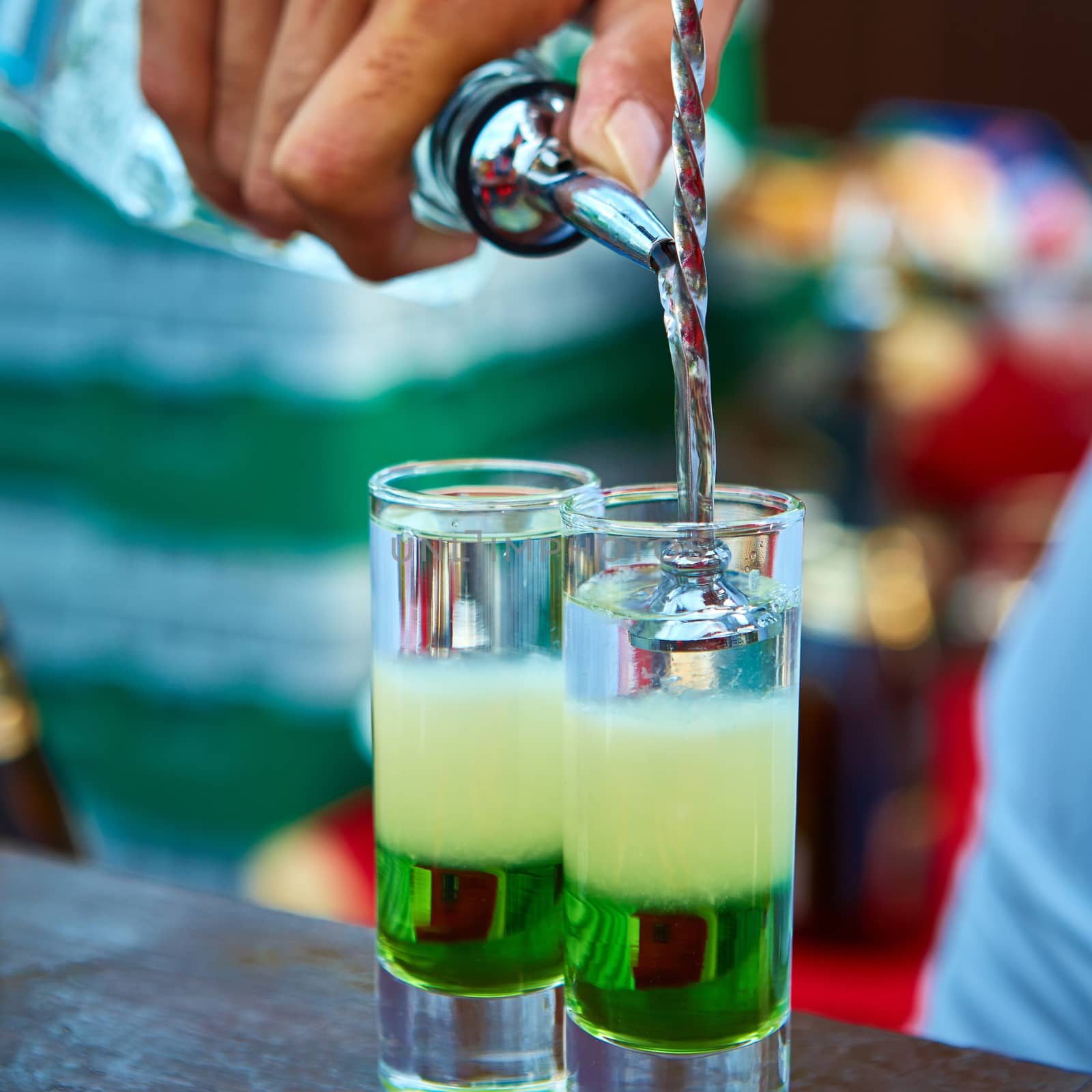 Layered cocktail Mexican green on the bar on the blur background.