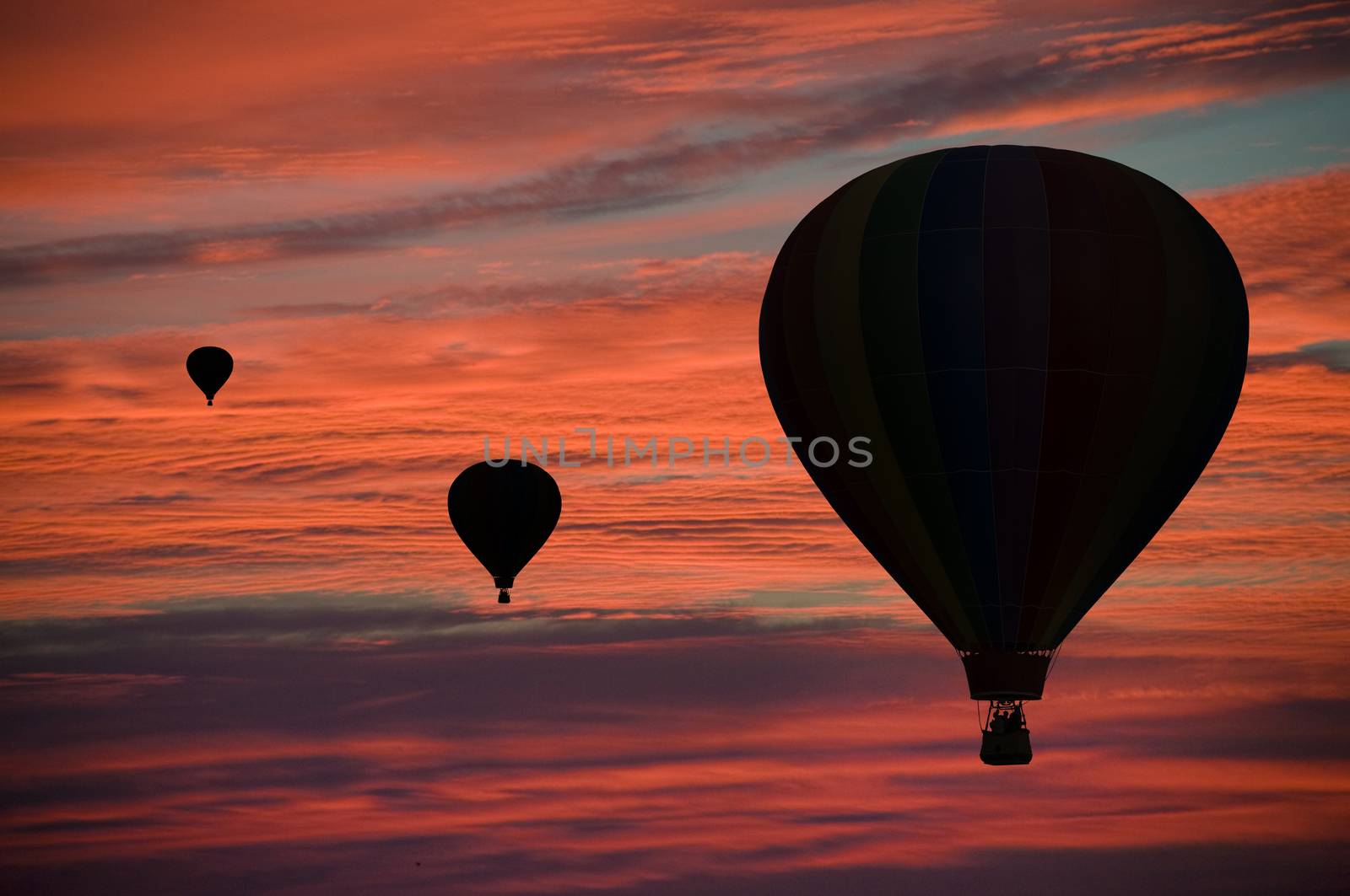 Hot-air balloons floating among pink and orange clouds at dawn