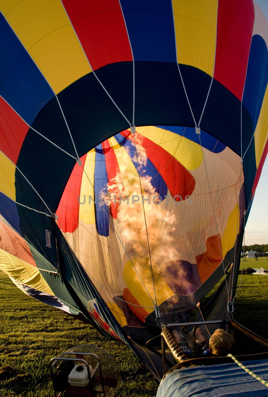 Hot air balloon being inflated in preparation for flight with flames shooting into the envelope.