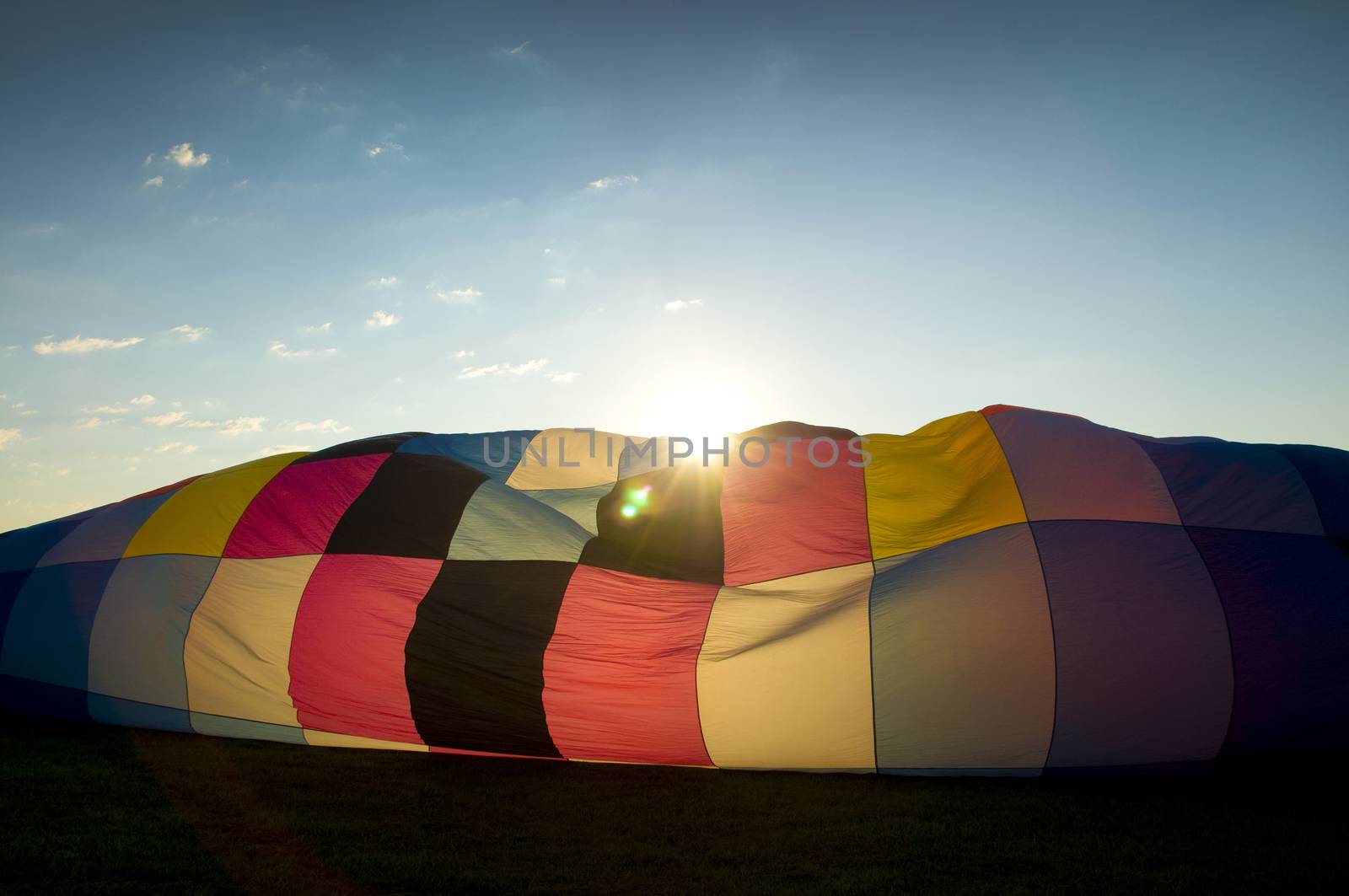 Sun peaking over the inflating envelope of a hot-air balloon