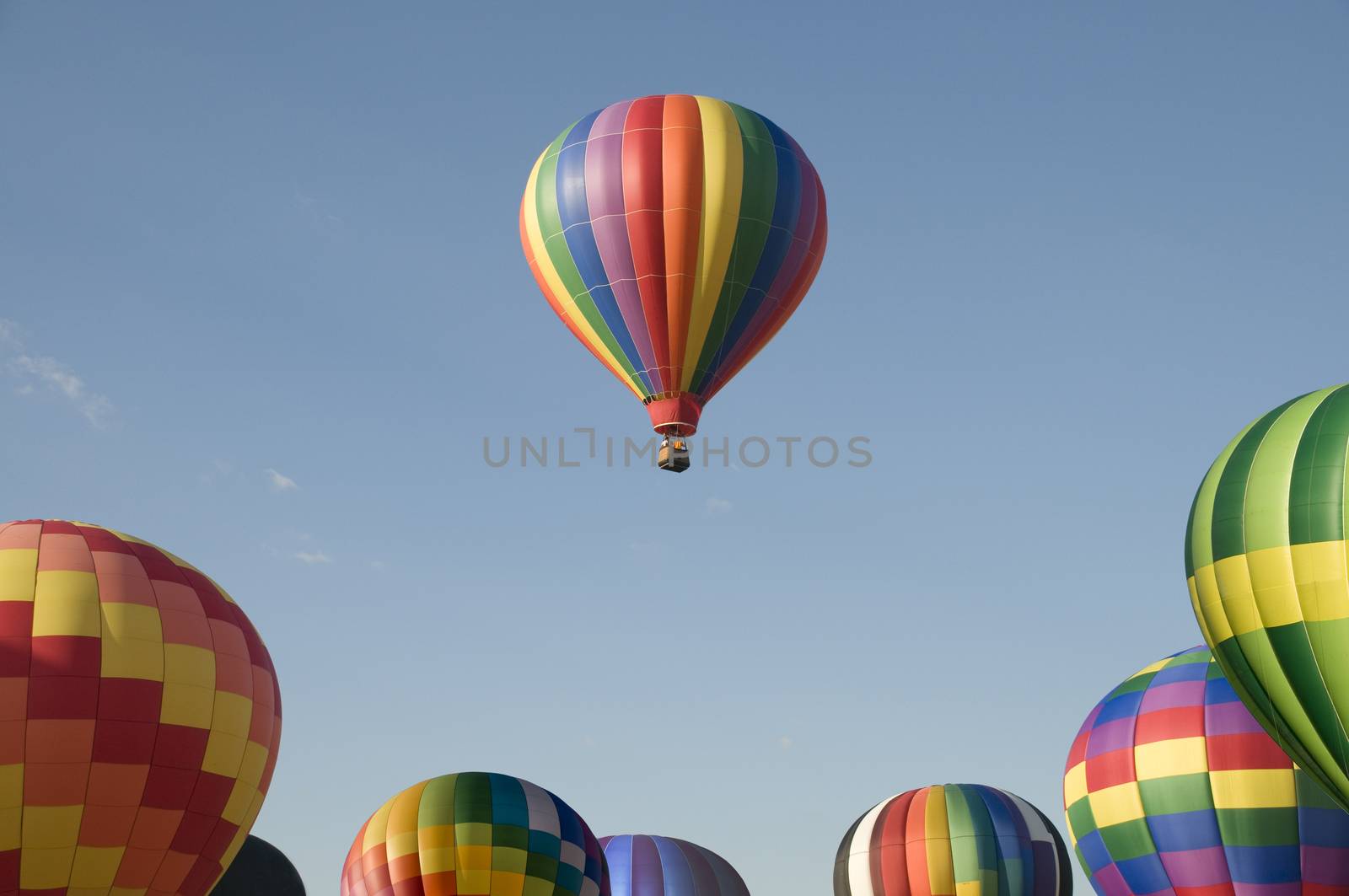 A single hot-air balloon floating above others at a balloon festival