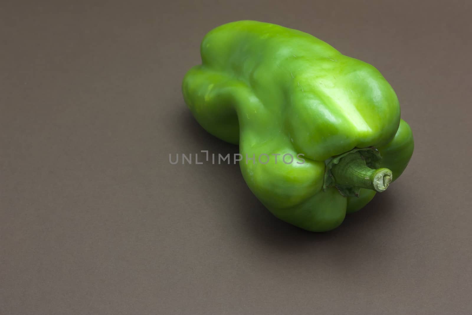 Green pepper isolated on a brown background to understand a concept to healthy eating