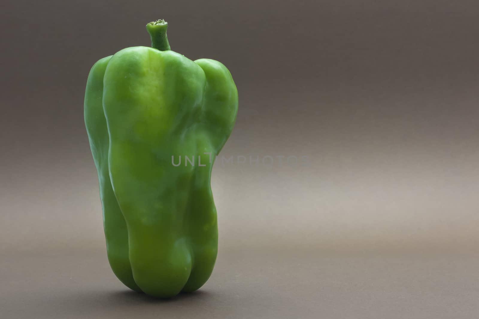 Green pepper isolated on a brown background to understand a concept to healthy eating