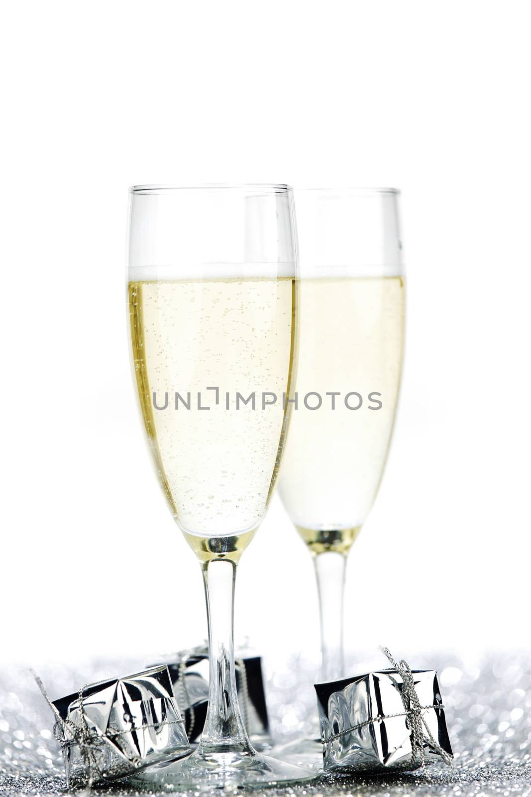 Glasses of champagne and christmas gifts on silver background