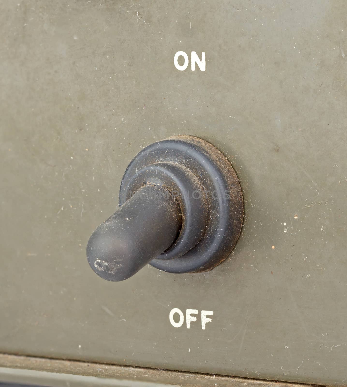 closed up old black toggle switch on green surface - off