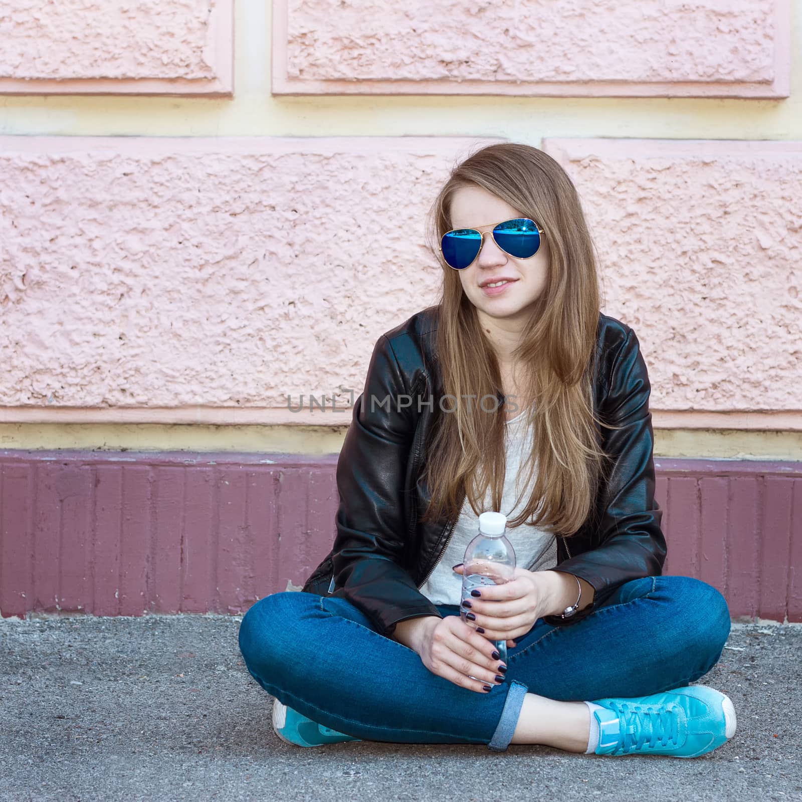 Girl in jacket, jeans and sunglasses sitting on pavement by victosha