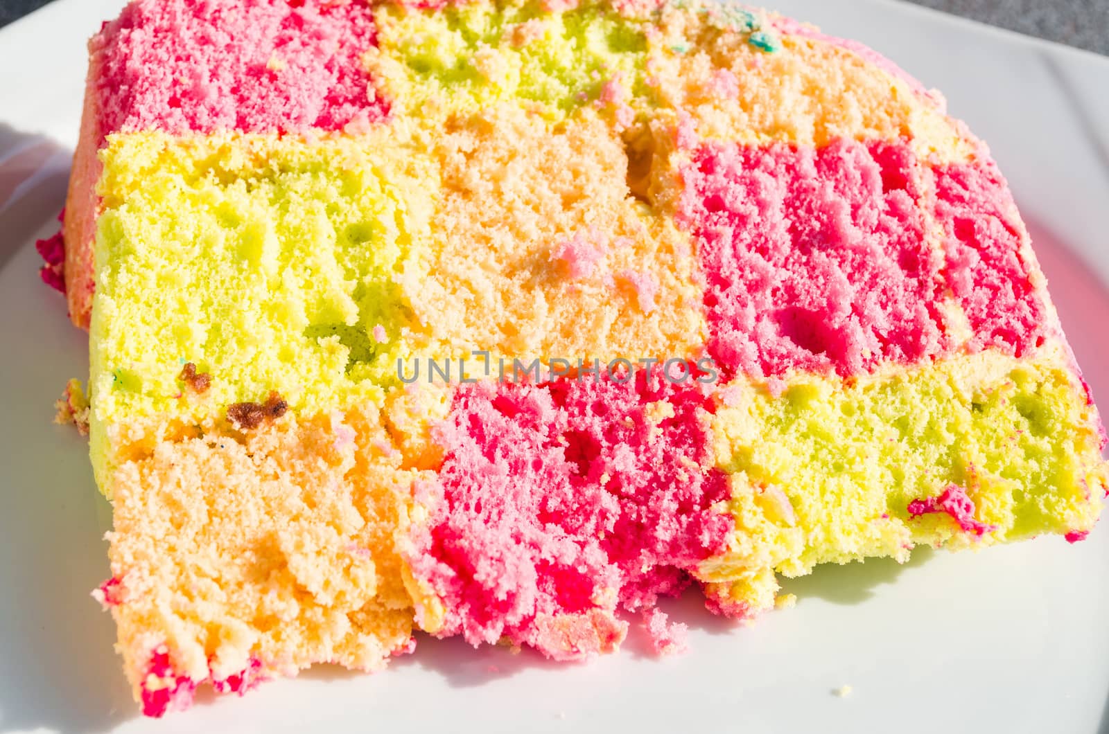 Delicious colorful checkered birthday cake. Cake on white plate.