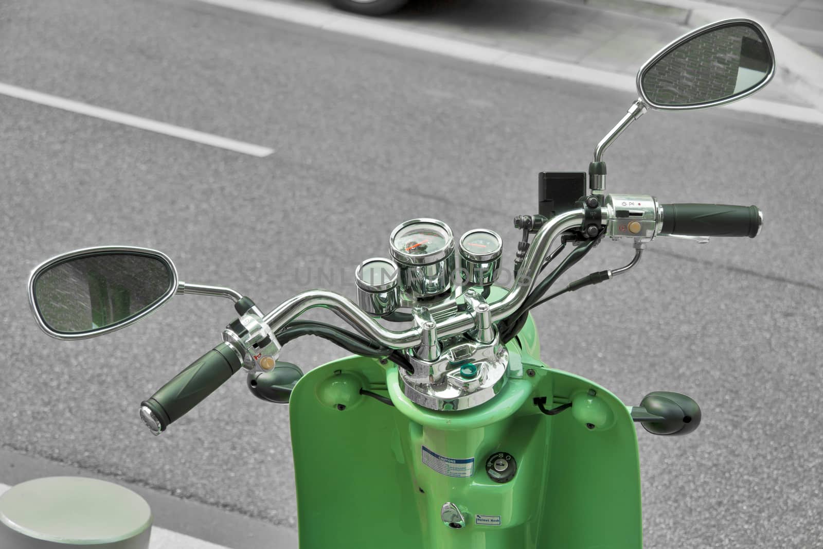 A green motor scooter is parked near the street.