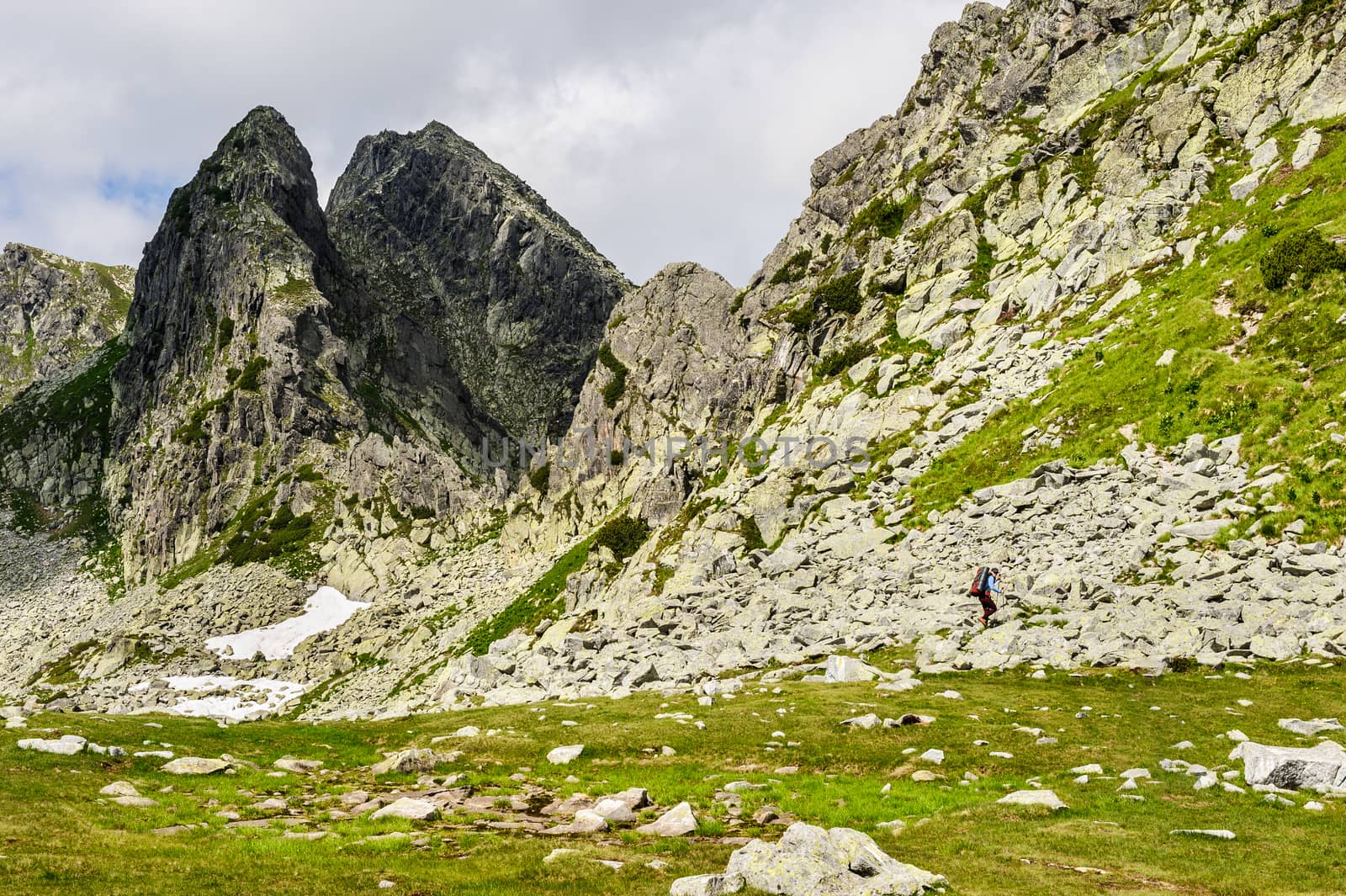 Young woman with backpack do summer hiking in the mountains. Retezat, Carpathians, Romania.