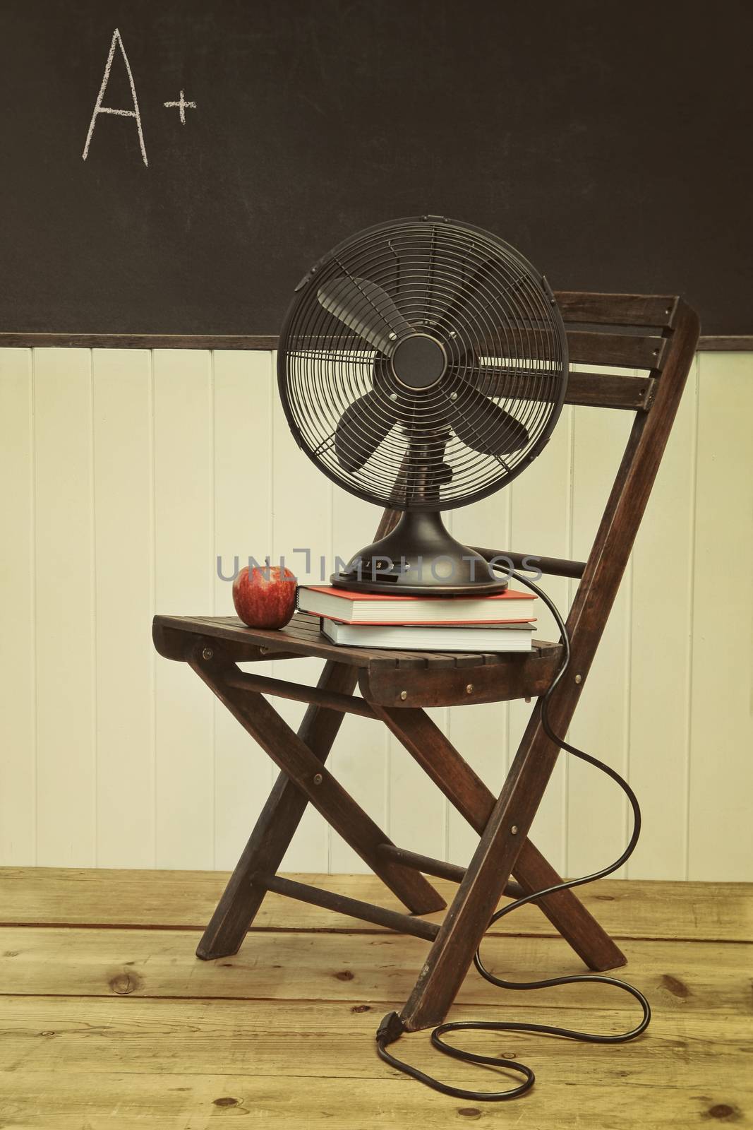 Old fan with apple and books on chair by Sandralise