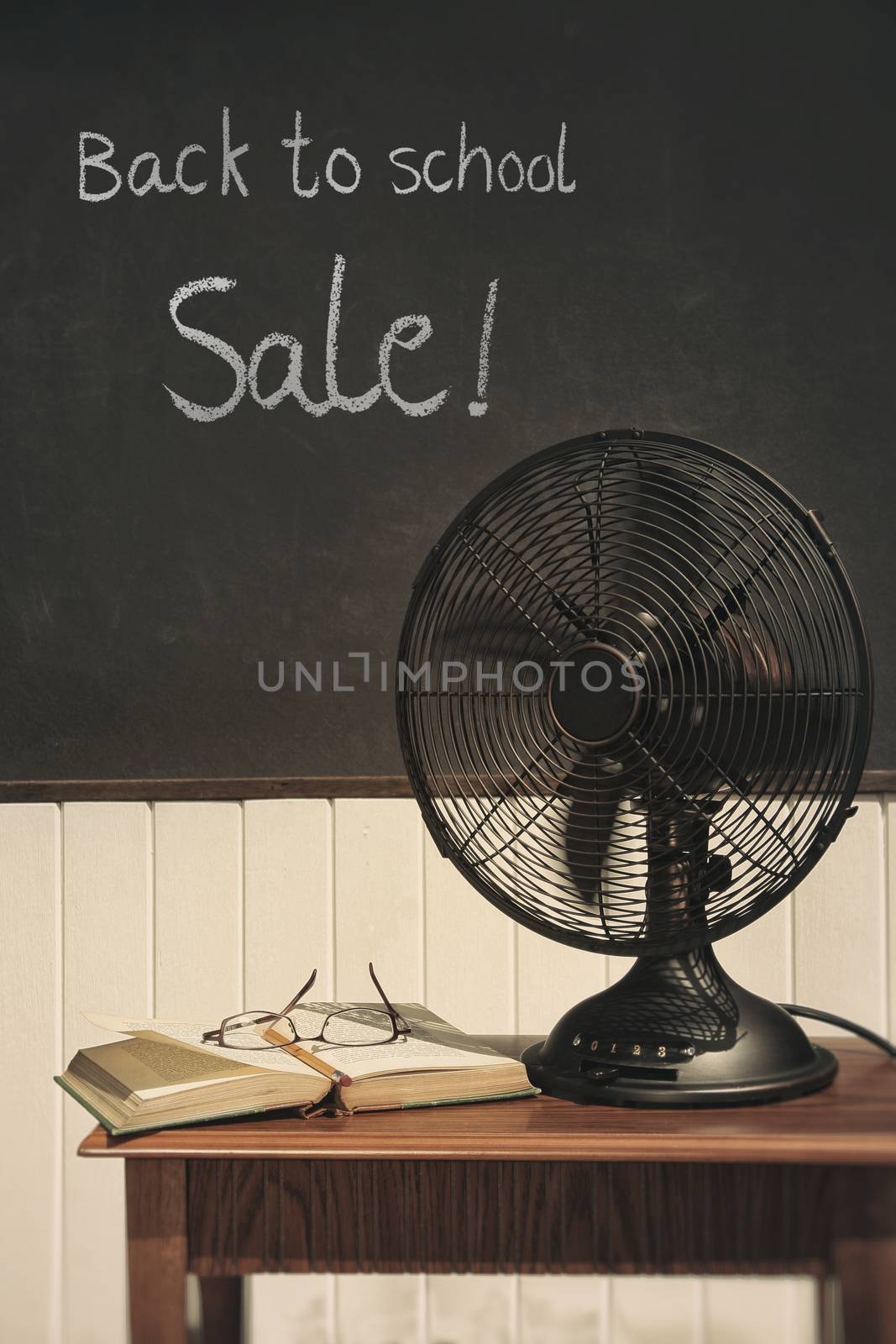 Vintage electric fan with book on table 