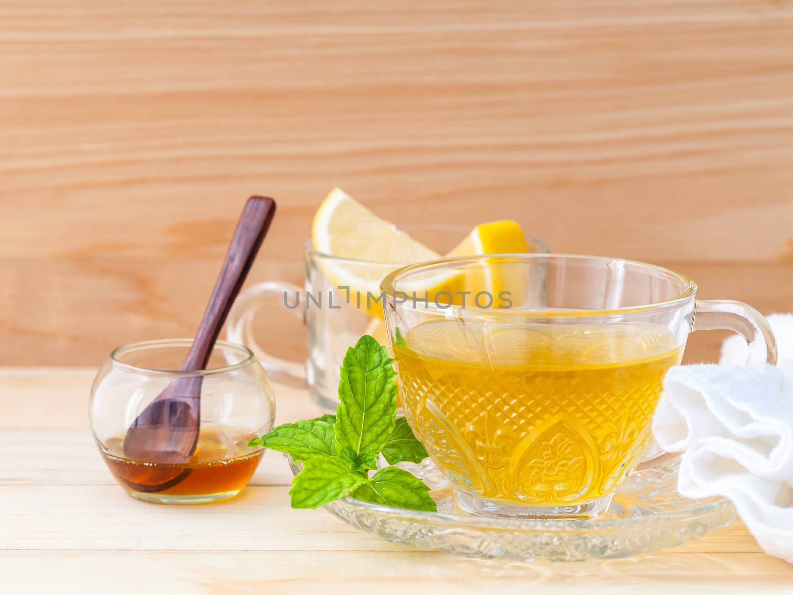 Cup of herbal tea with fresh green mint ,honey and lemon on wood by kerdkanno