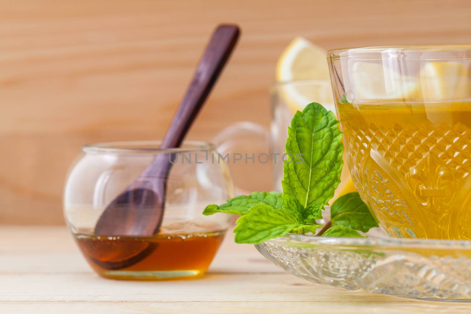 Cup of herbal tea with fresh green mint ,honey and lemon on wood by kerdkanno