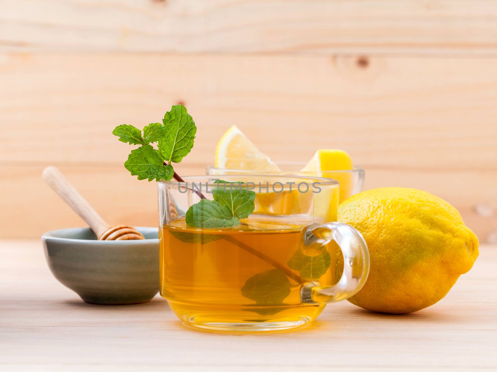 Cup of herbal tea with fresh green mint ,honey and lemon on wood by kerdkanno