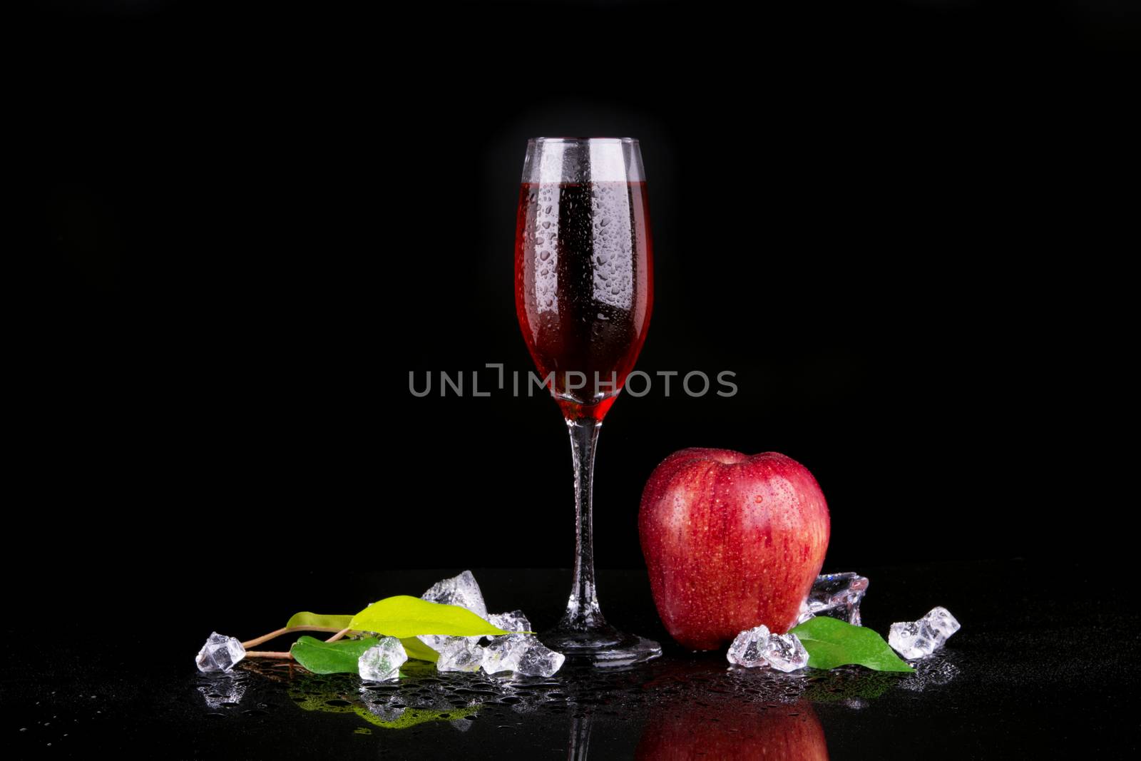 Red apple with a glass of champagne on black background
