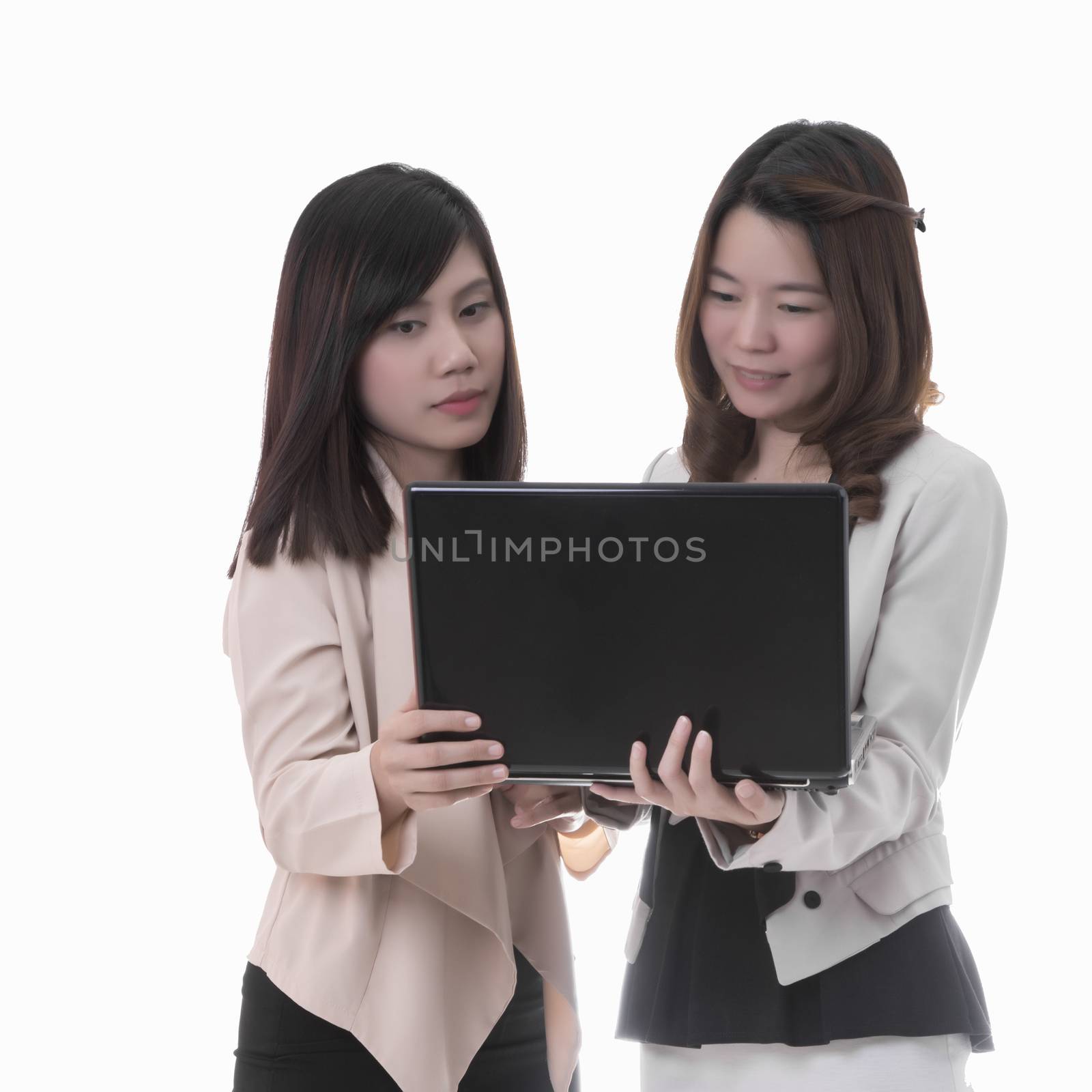 Two asian business woman in office, discussing notebook
