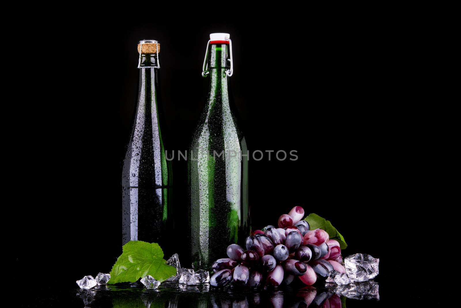 Red grape with wine bottle on black background