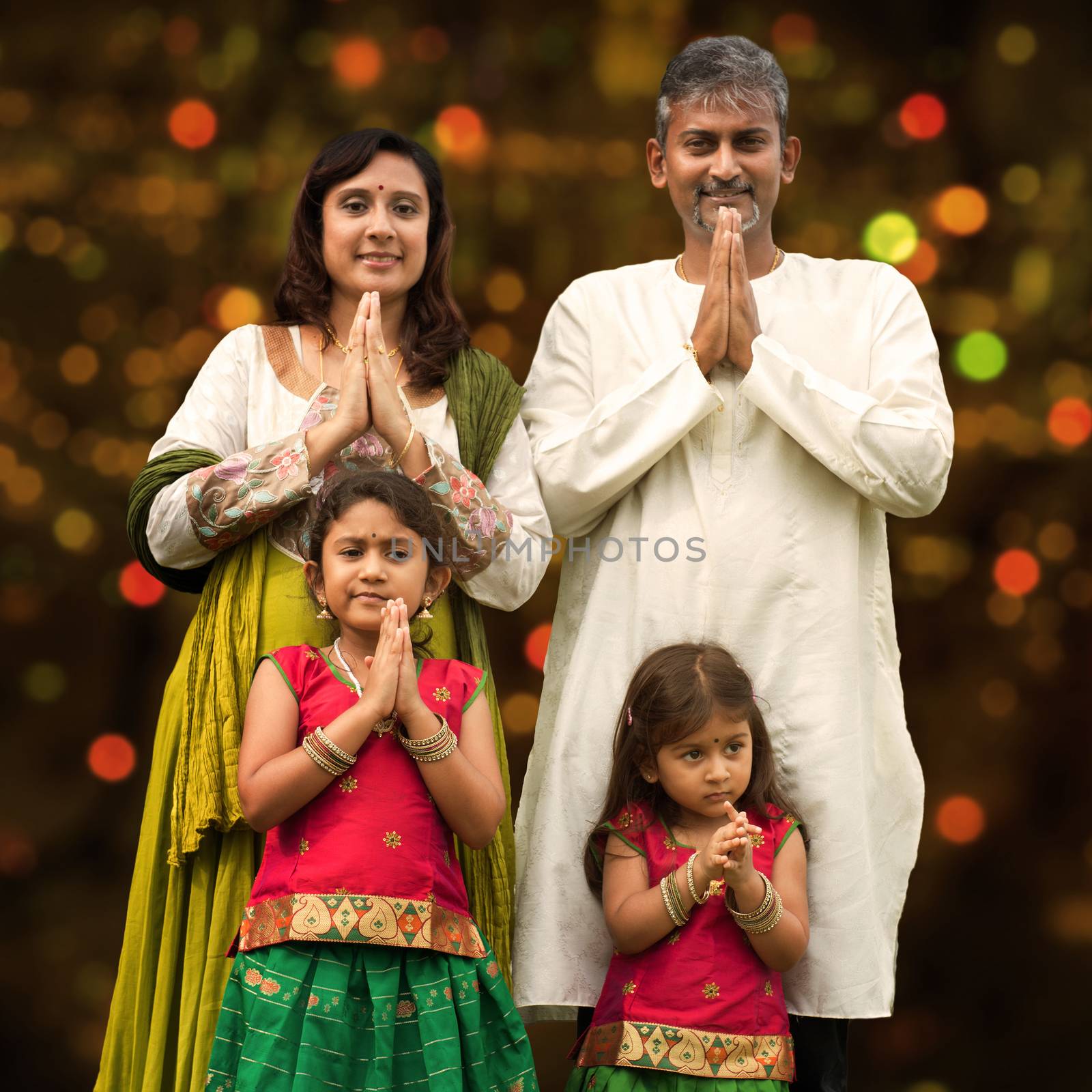 Indian family greeting on Diwali, festival of lights, inside a temple.