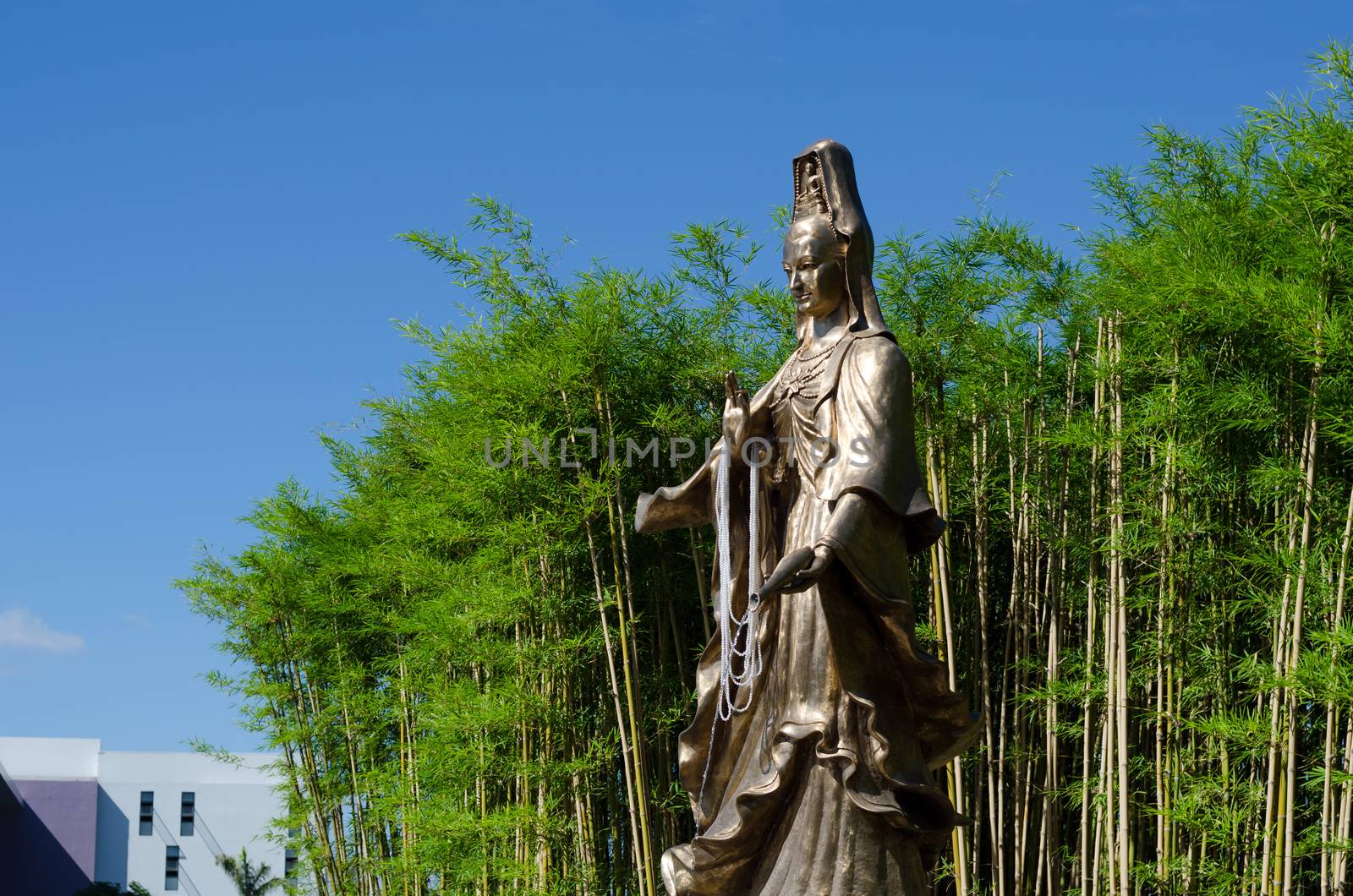 Guan Yin, Goddess of Mercy, bronze statue with Bamboo Garden in background