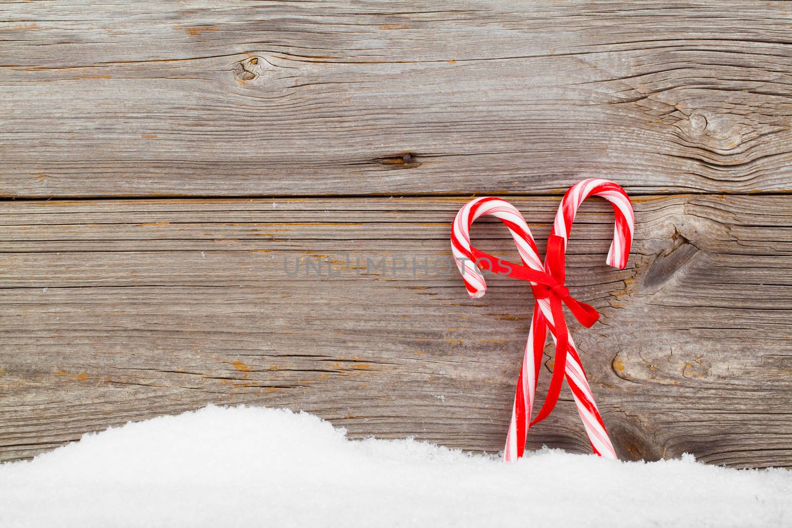 Colorful striped red and white Xmas candy canes with winter snow by motorolka