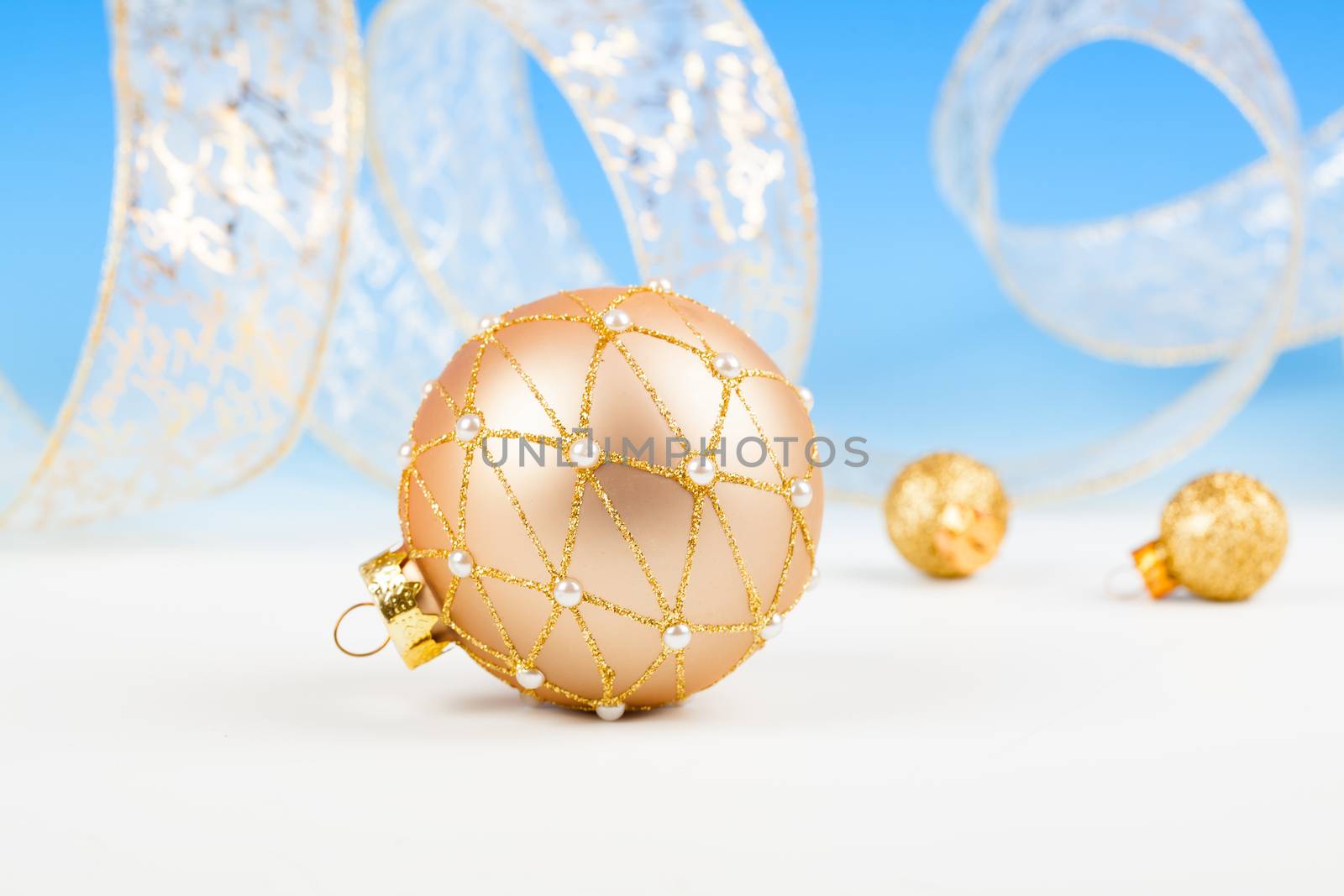 Christmas balls with ribbon on snow, on blue background