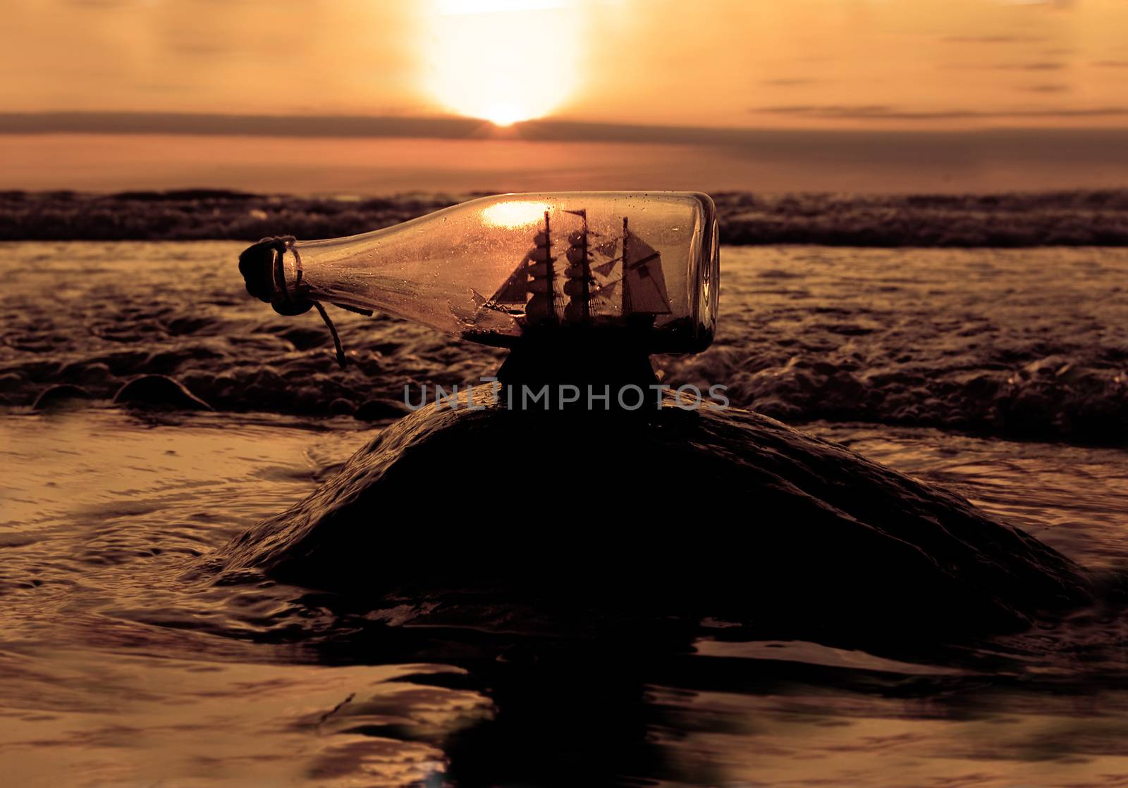 Souvenir conceptual image. Ship in a bottle against sea at sundown in summer.