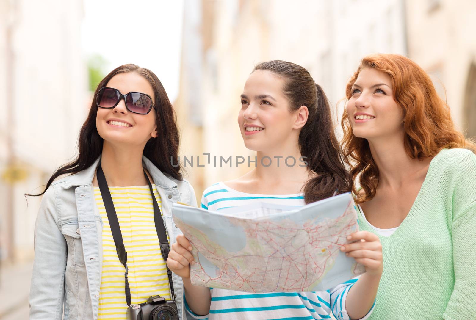 smiling teenage girls with map and camera by dolgachov