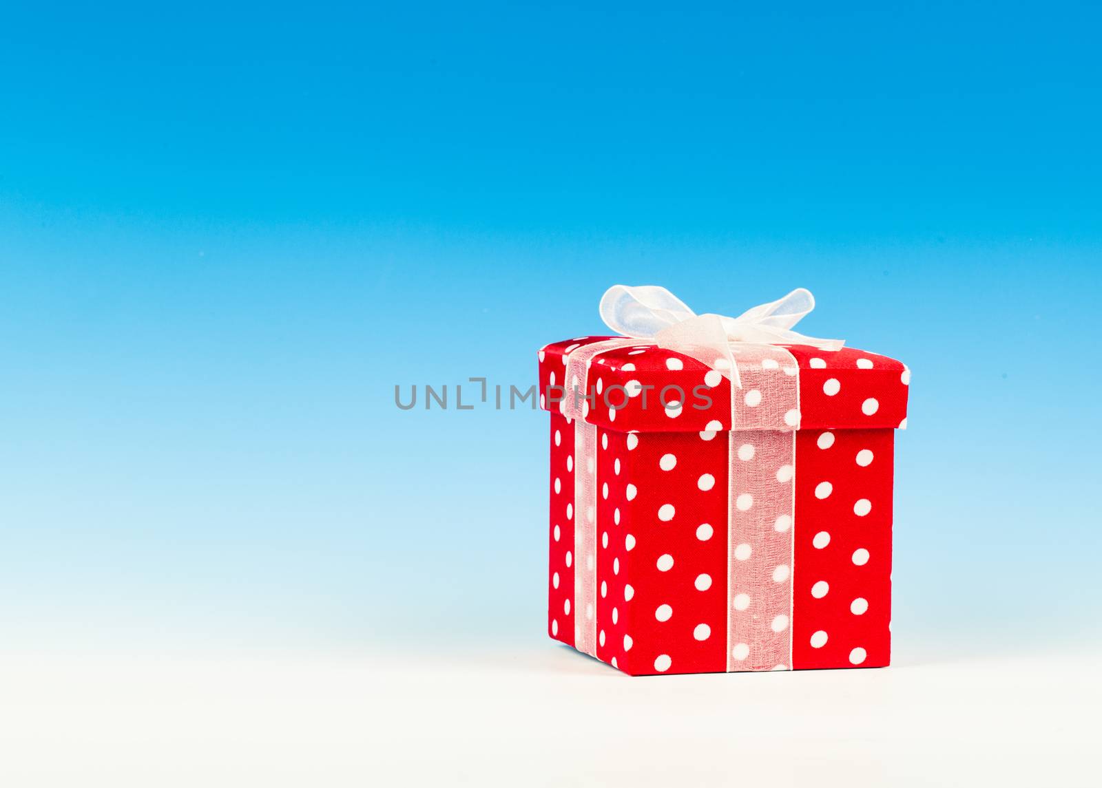 red gift box, polka dots with bow on blue background