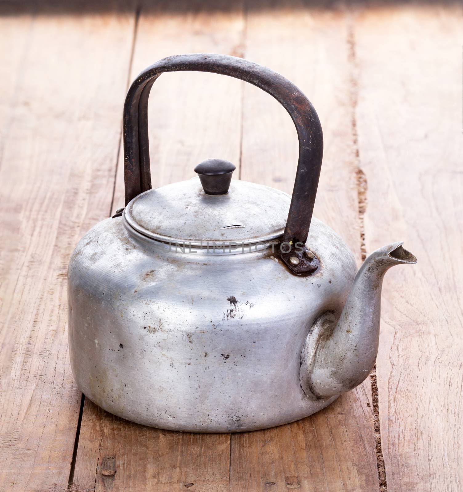 dirty classic aluminum kettle on wooden background by supersaiyan