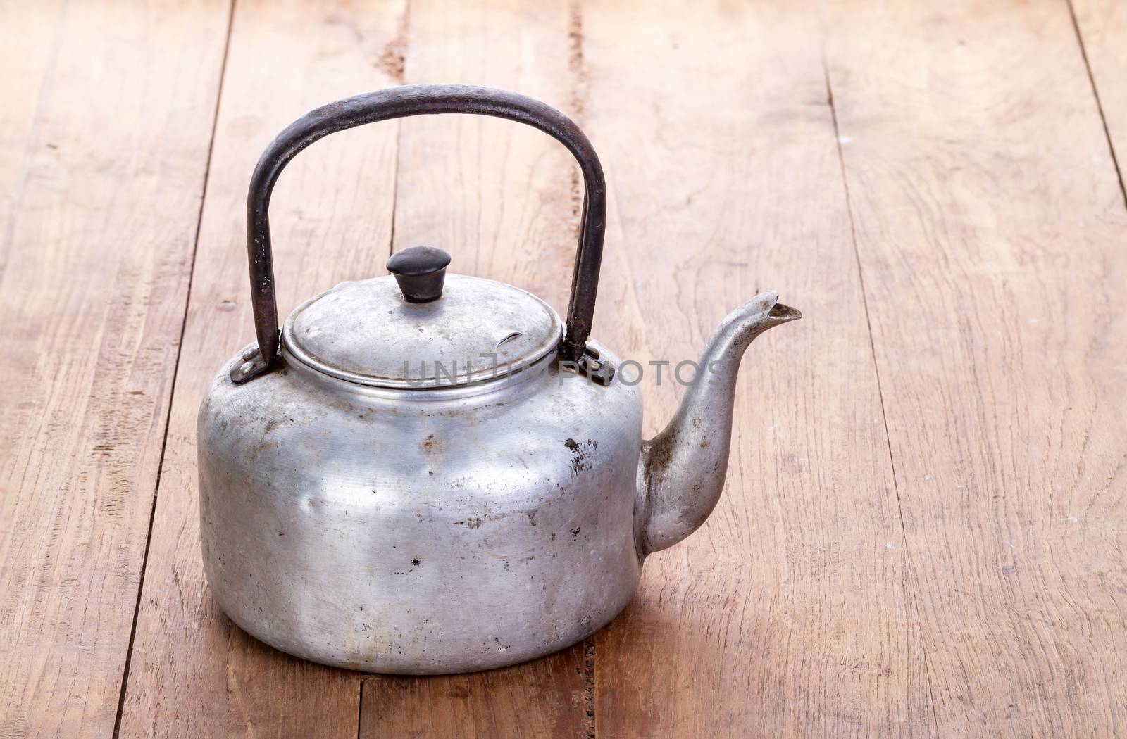 dirty classic aluminum kettle on wooden background by supersaiyan