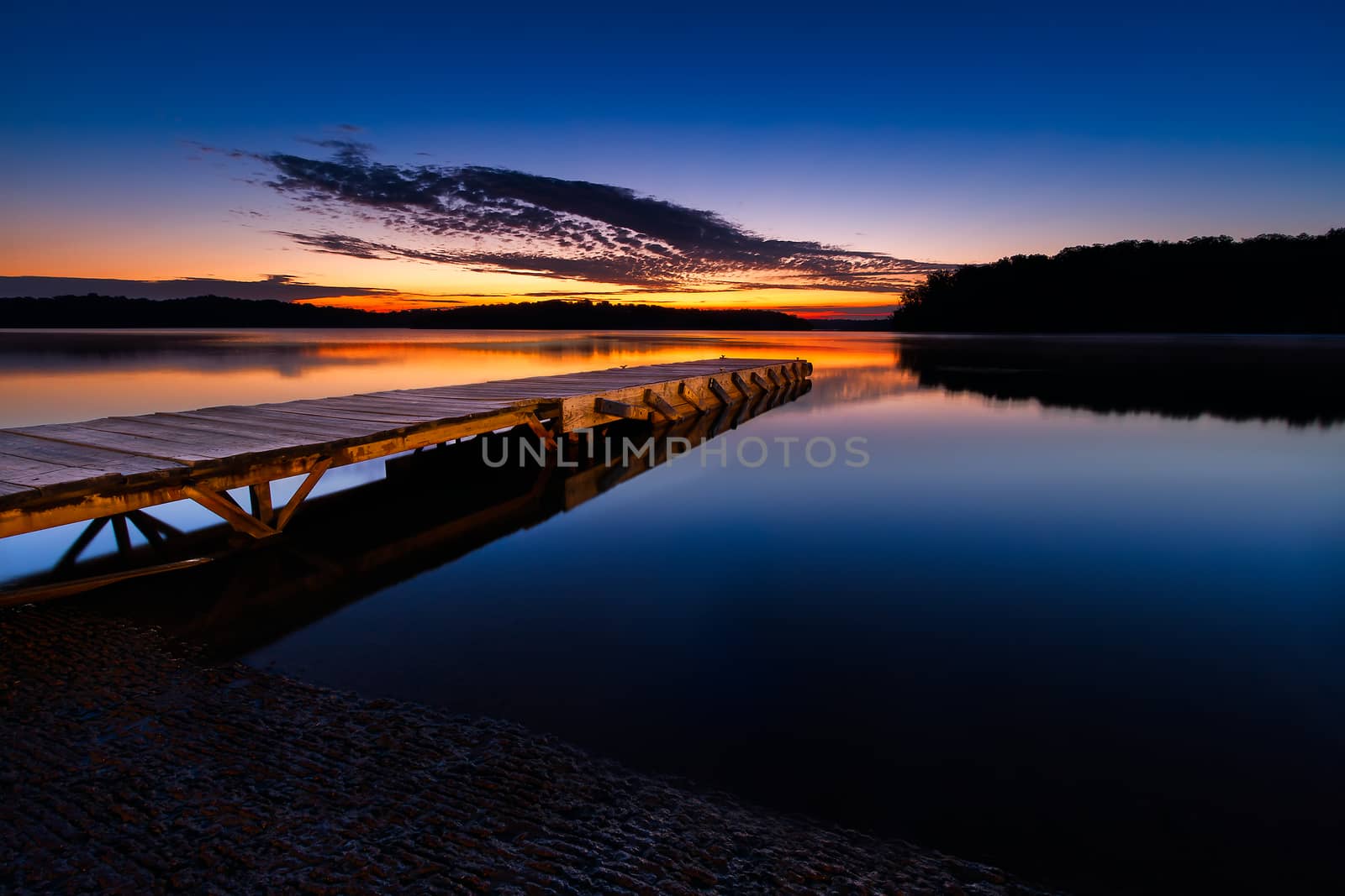 A boatramp and a loading dock before sunrise with vibrant colors in the sky.