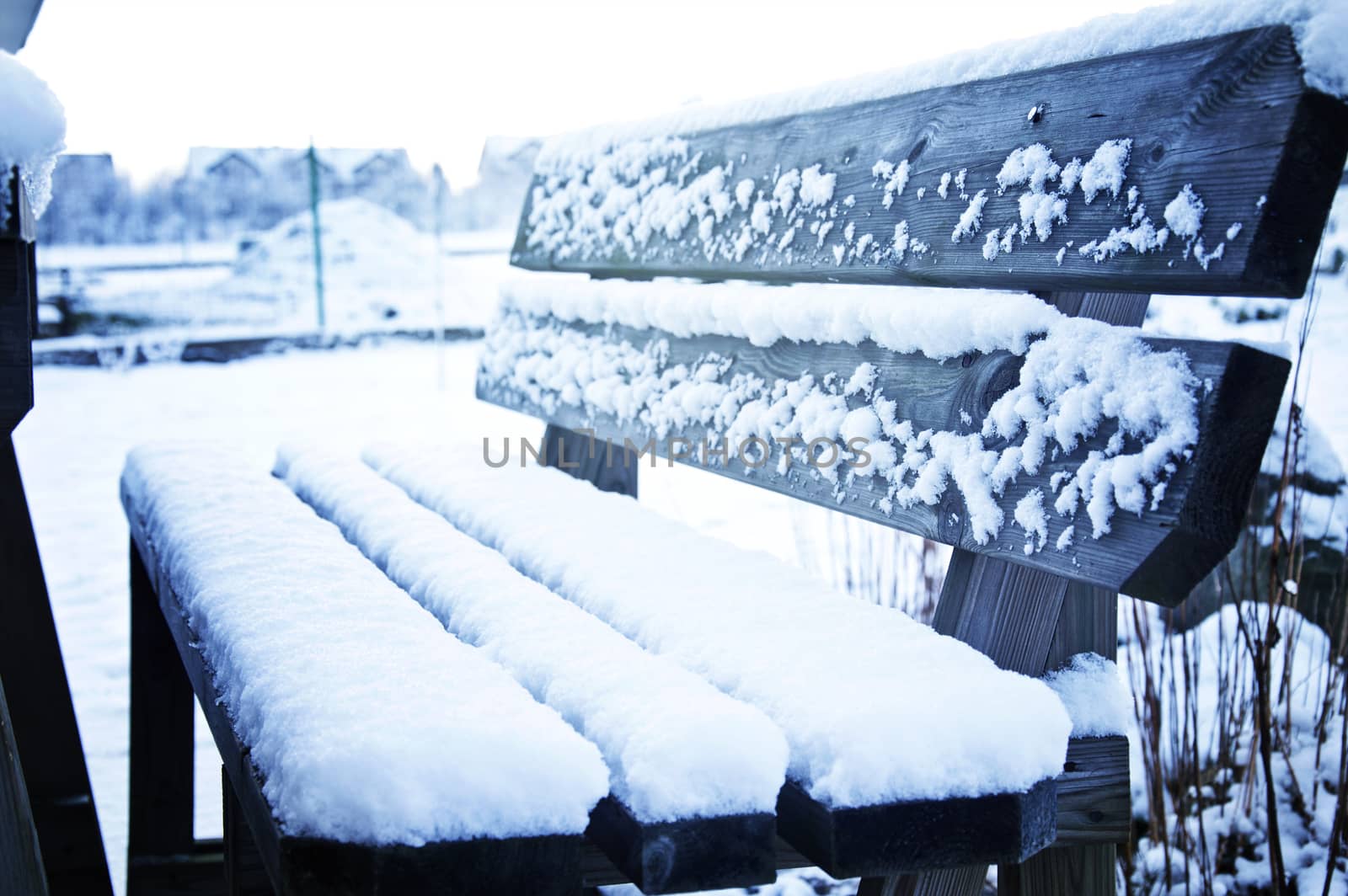 Winter and snow conceputal image. Bench covered with snow.