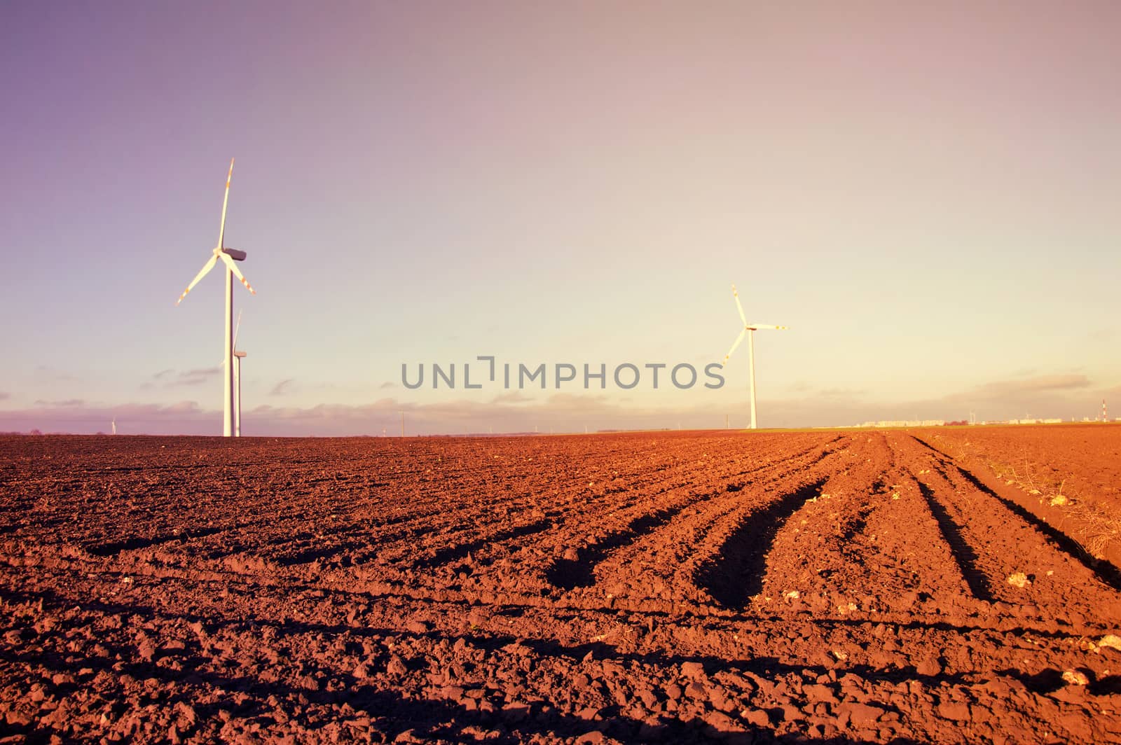 Windmill on the plowed field. Vintage sunburst picture. Alternative energy.