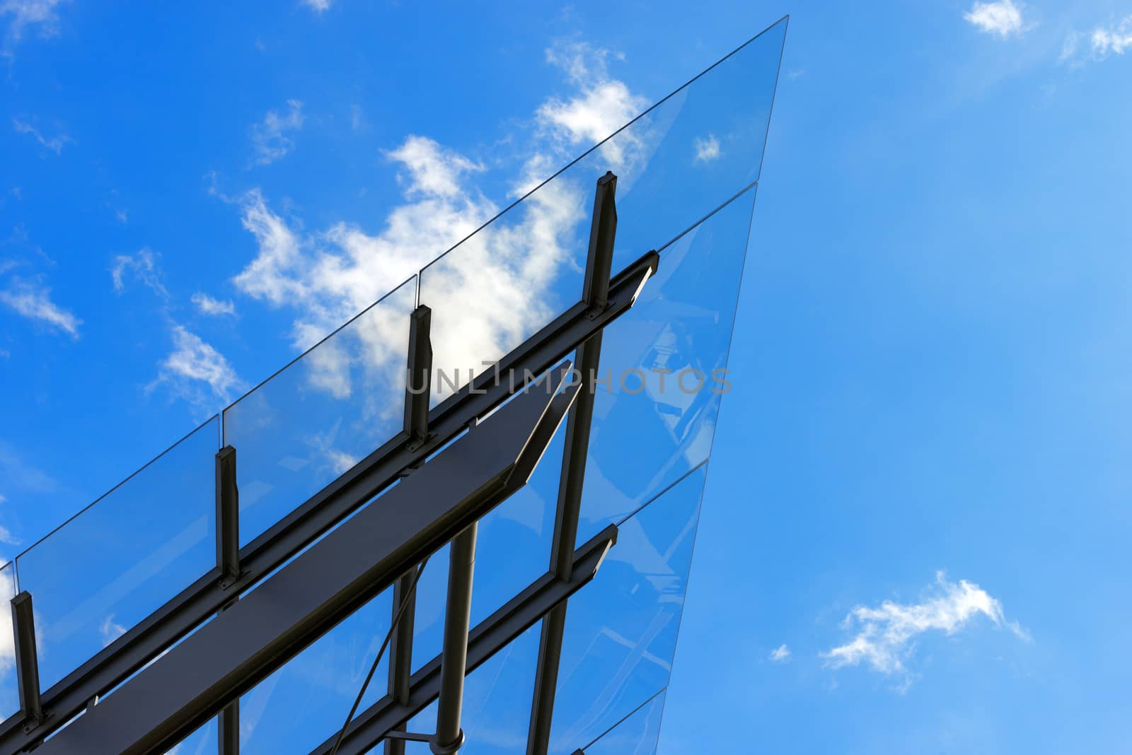 Detail of steel and glass roof of a modern building with blue sky and clouds