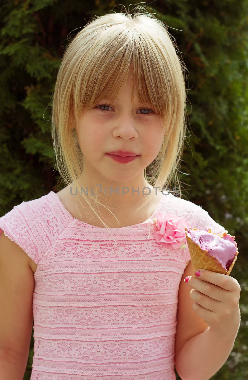 Girl 6 years old in a pink dress with ice cream in hand
