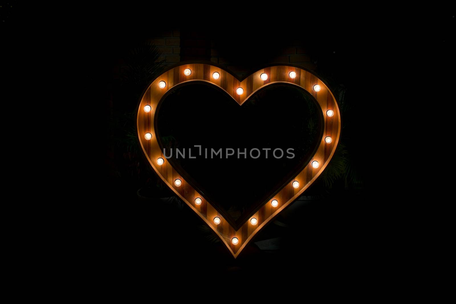 Heart sign with light bulb isolate on black background