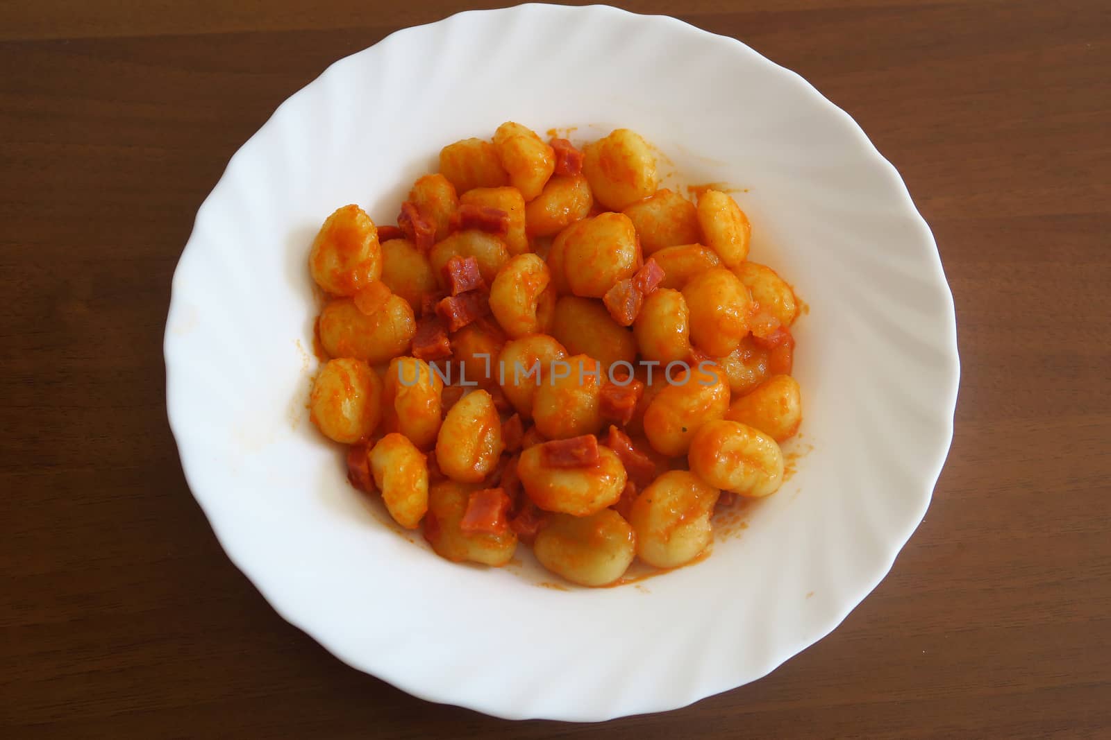 Potato dumplings, a typical Italian pasta, here served with tomato sauce and ham